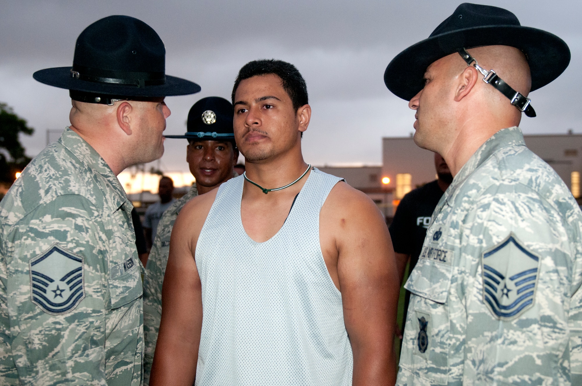 Former military training instructors Master Sgt. Gregory Wasson (left), Senior Master Sgt. Theodore Guillory and Master Sgt. John Mascolo (right) motivates a University of Hawaii football player during the physical training session after their 5 a.m. basic training style wake-up call Aug. 14 at Joint Base Pearl Harbor-Hickam. Air Force and Navy servicemembers took part in a team building exercise with the team for an early morning physical training session. The Warriors are scheduled to be on the road for their opener Sept. 1, in Los Angeles, against the University of Southern California Trojans. (U.S. Air Force photo/Staff Sgt. Mike Meares)