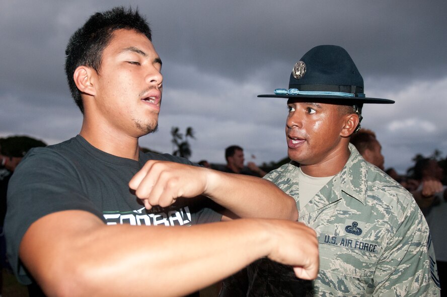 Senior Master Guillory, 56th Air and Space Communications Squadron and former military training instructor, motivates a University of Hawaii football player during the physical training session after their 5 a.m. basic training style wake-up call Aug. 14 at Joint Base Pearl Harbor-Hickam. Air Force and Navy servicemembers took part in a team building exercise with the team for an early morning physical training session. The Warriors are scheduled to be on the road for their opener Sept. 1, in Los Angeles, against the University of Southern California Trojans. (U.S. Air Force photo/Staff Sgt. Mike Meares)