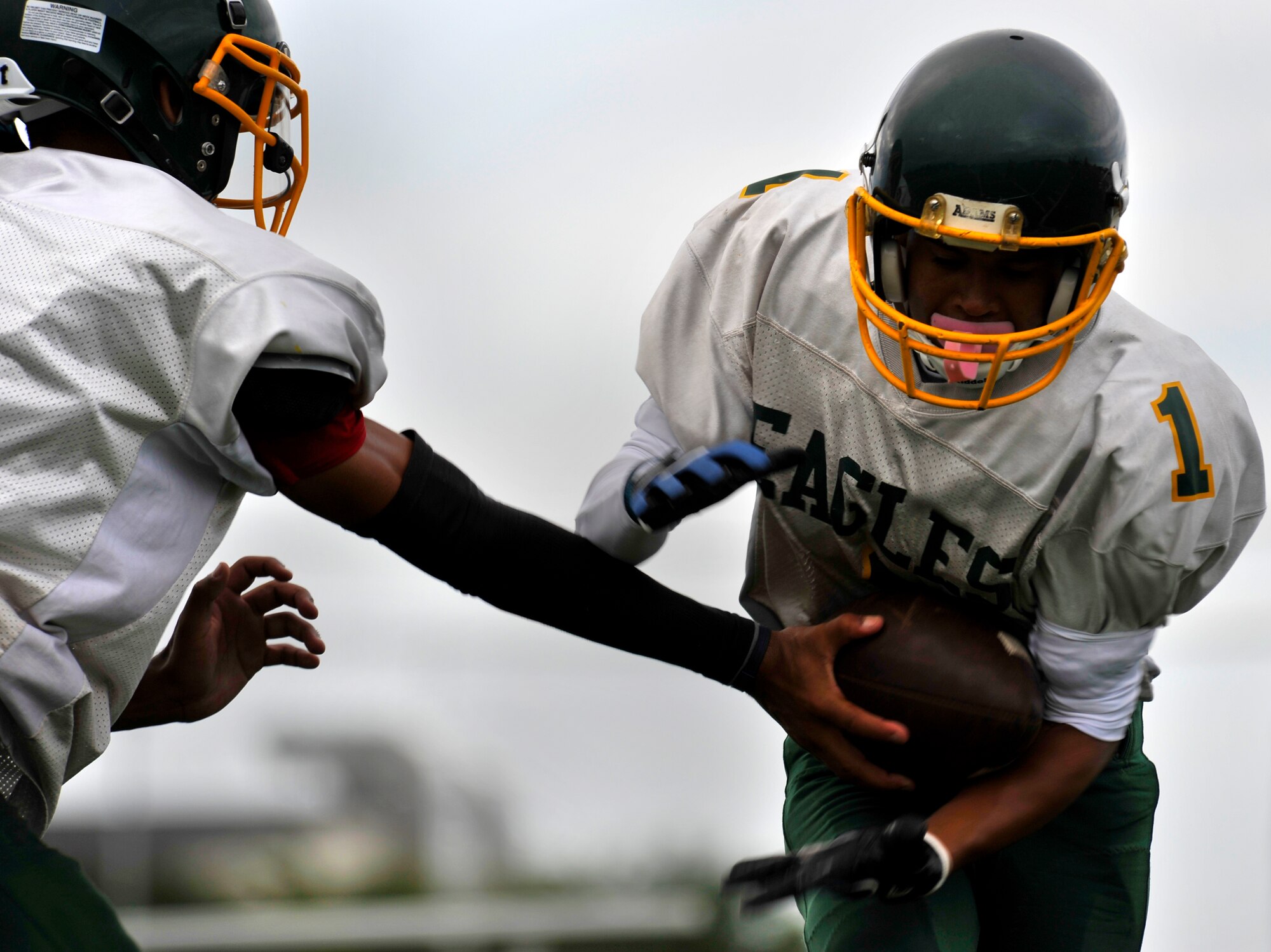 Edgren Eagles quarterback Tristan Jefferson hands the ball off to running back Tyrone Balcasa during the Edgren High School football practice at Misawa Air Base, Japan, Aug. 15, 2012. Quarterbacks and running backs worked with each other on plays and to ensure ball control. (U.S. Air Force photo by Airman 1st Class Zachary Kee/Released)