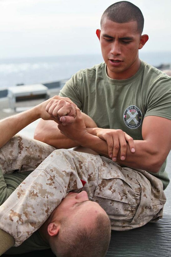 Sergeant Andy Alonso (right), landing support chief, Landing Support Section, Transportation Support Detachment, Combat Logistics Battalion 15, 15th Marine Expeditionary Unit, demonstrates a grappling move  on Cpl. Courtland Lambert, a landing support specialist with the unit, while instructing Marines in the Marine Corps Martial Arts Program on the flight deck of the USS Rushmore, Aug. 16. The 15th MEU is embarked as part of the Peleliu Amphibious Ready Group during Certification Exercise, their final training before their deployment this fall. Alonso, 25, is from New York City, and Lambert, 25, is from Clarksville, Tenn.