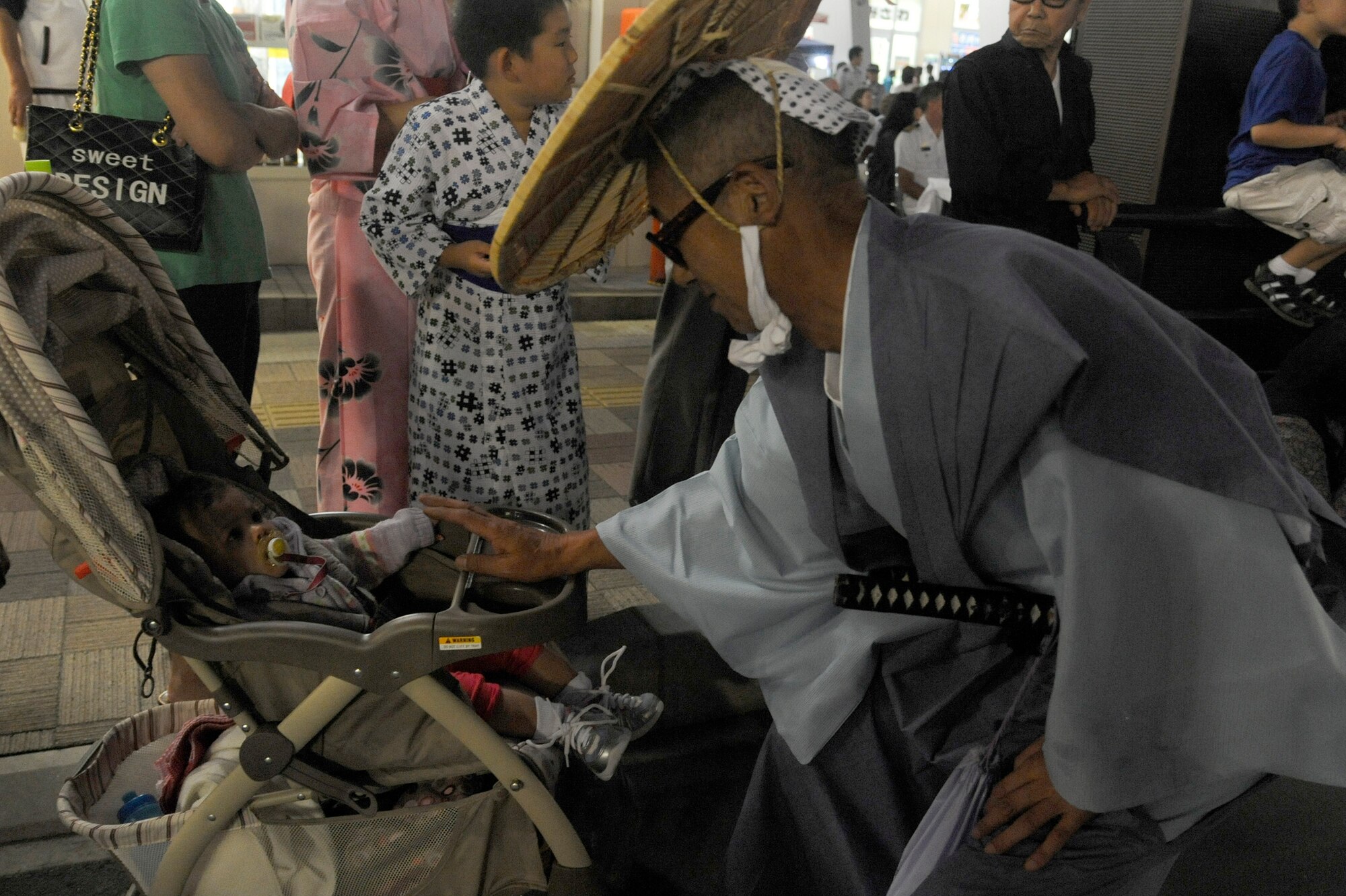 A parade participant stops to greet a child from Misawa Air Base during the summer festival parade Aug. 19, 2011. Families of Misawa Air Base and the local community lined the streets of downtown Misawa City for the float parade. This year the parade will be on Aug. 25 and will run in front of American Park outside the main gate. (U.S. Air Force photo/Tech. Sgt. Marie Brown)

