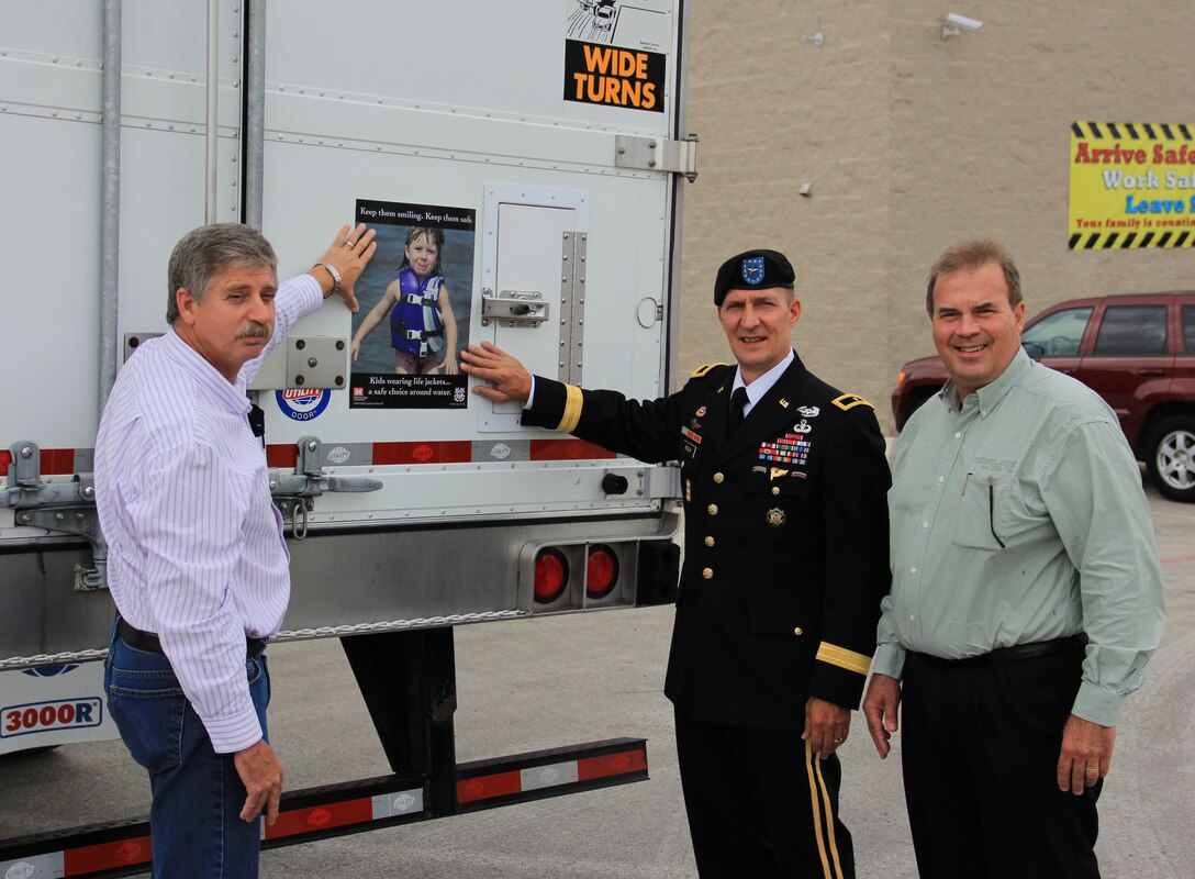 That's a big 10-4: Brig. Gen. Thomas W. Kula, SWD commander, center, joins with Mr. Jim Franck, right, president of National Carriers, Inc., and Johnny Branstine, maintenance director, to place a water safety sign on one of the 900 tractor trailer trucks owned by the company.  