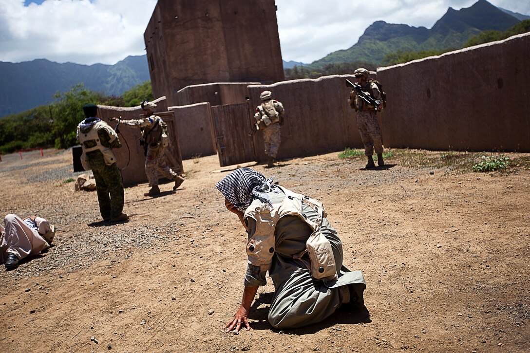 A non-compliant role-player wipes simulated OC spray off his face after being subdued by Sgt. Daniel McCaughern (third from left), a squad leader with 1st Platoon, India Company, 3rd Battalion, 3rd Marine Regiment, and 24-year-old native of Deer Park, N.Y., during non-lethal weapons training in a simulated urban village on Marine Corps Training Area Bellows, Hawaii, Aug. 15, 2012. The training was part of a two-week test readiness review fielded by the Quantico, Va.-based Joint Non-Lethal Weapons Directorate and the Marine Corps Forces, Pacific Experimentation Center. The DoD Non-Lethal Weapons Program, headed by Commandant of the Marine Corps Gen. James Amos, trains operating forces on escalation of force options to minimize casualties and collateral damage, said Kelley Hughes, a directorate spokesperson.