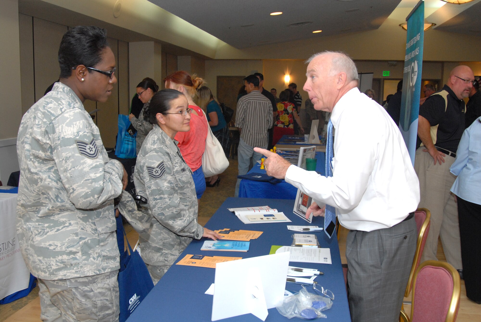 Airmen speak with a representative from Western International University Aug. 15 at the annual Edwards Education Fair.  Forty colleges and universities showed up for the fair to show prospective students what's out there in terms of degree programs, both on campus and online. (U.S. Air Force photo by Kenji Thuloweit)