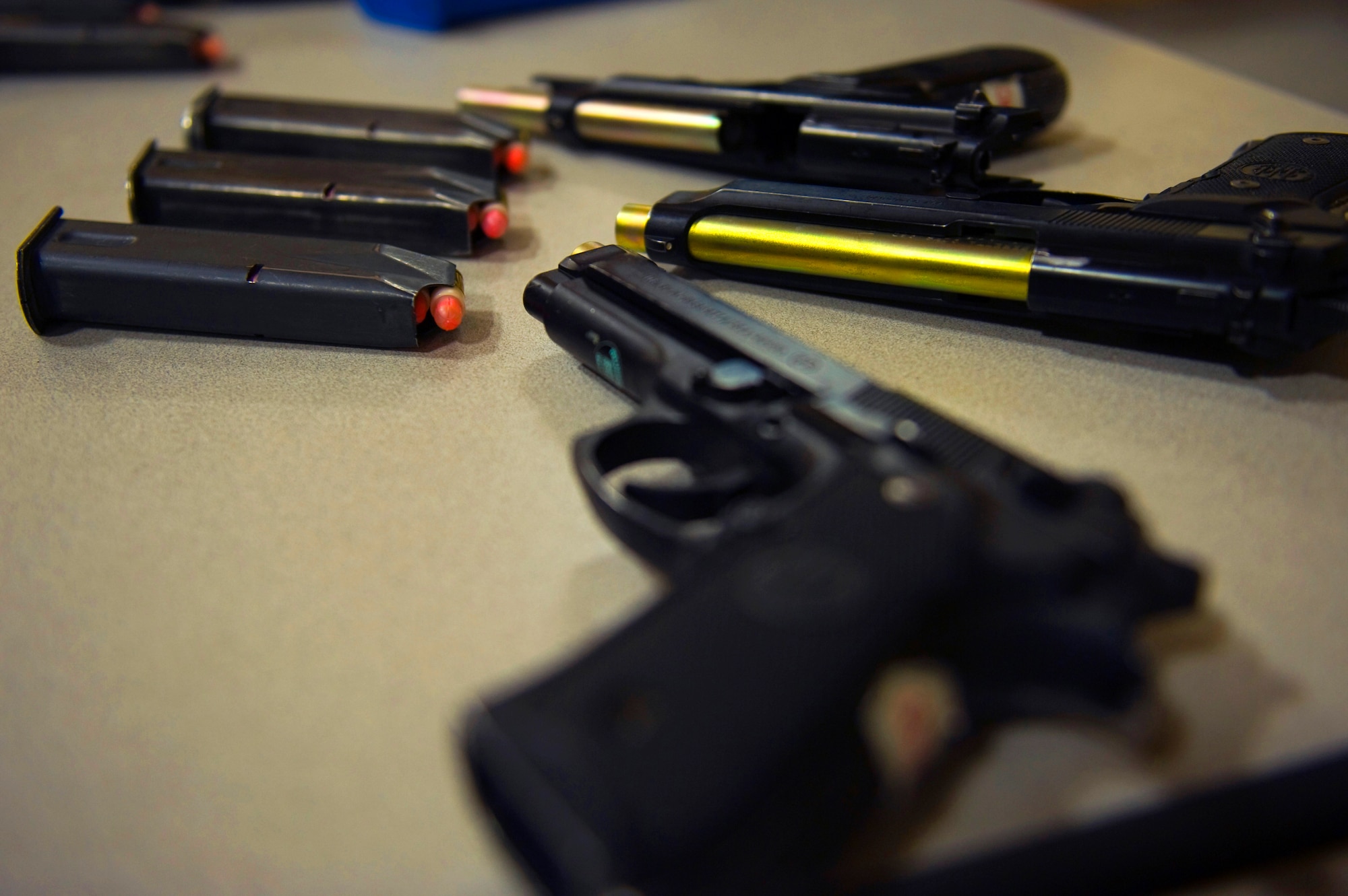 The barrels of M9 pistols are swapped with gold training barrels at the 99th Security Forces Squadron shoothouse Aug. 15, 2012, at Nellis Air Force Base, Nev. The gold color indicates that only simulated munitions can be fired. (U.S. Air Force photo by Staff Sgt. William P.Coleman)
  

