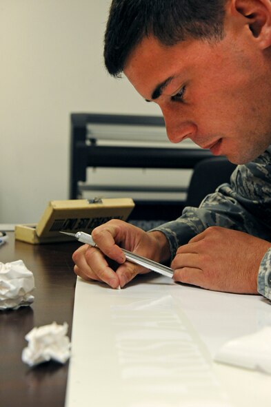 Senior Airman Robert Schwab, 2nd Maintenance Squadron, removes excess vinyl from a vinyl sheet on Barksdale Air Force Base, La., Aug. 20. The vinyl cutter is used to create graphics and tail markings for aircraft and equipment. (U.S. Air Force photo/Airman 1st Class Micaiah Anthony)(RELEASED)