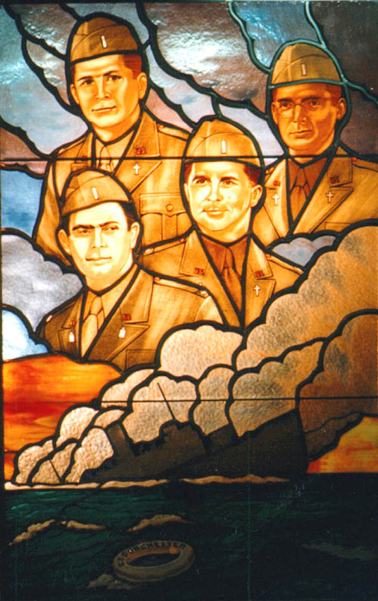 BUCKLEY AIR FORCE BASE, Colo.-- A stained glass window at the Pentagon Chapel depicts the four chaplins who sacrificed themselves to save others onboard the U.S. Army Transport, The Dorchester, after it was torpedoed by a German submarine Feb. 3, 1943. Chaplains of different faiths, Lt. George L. Fox, Lt. Alexander D. Goode, Lt. Clark V. Poling and Lt. John P. Washington were all aboard the vessel as it sank. They handed out life vests to those who did not have them, even giving up their own life vests when supplies ran out. As the ship sank, survivors from the lifeboats saw the chaplains link arms with their heads bowed. Survivors from the ship heard the chaplains praying in different langauages. These chalpains made the ultimate sacrfice, praying together despite their different religious beliefs. The stained glass window depicts the four chaplains in the clouds above the sinking ship with a life ring floating in the water depicting the ship's name, The Dorchester. (U.S. Pentagon)