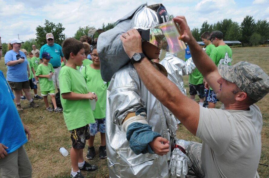 Master Sgt. Anthony Pacewicz helps a boy scout from northern Ohio try on firefighting gear at White Star Park, Gibsonburg, Ohio, July 26, 2012.  Each year the camp program has a different theme; this year’s theme consisted of American Heroes, which included military members, Ottawa county Sheriff’s office, the Port Clinton police K9 unit and a local fire department underwater rescue team.  (U.S. Air Force photo by Senior Airman Amber Williams/Released)