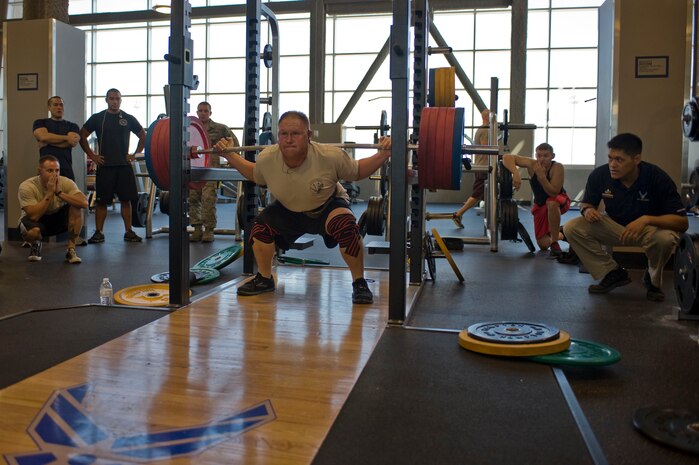 A U.S. Air Force Airman squats while judges and spectators watch during a powerlifting competition at the Warrior Fitness Center Aug. 15, 2012, at Nellis Air Force Base, Nev. This event is open to all base personnel that are 18 and older. (U.S. Air Force photo by Airman 1st Class Christopher Tam)