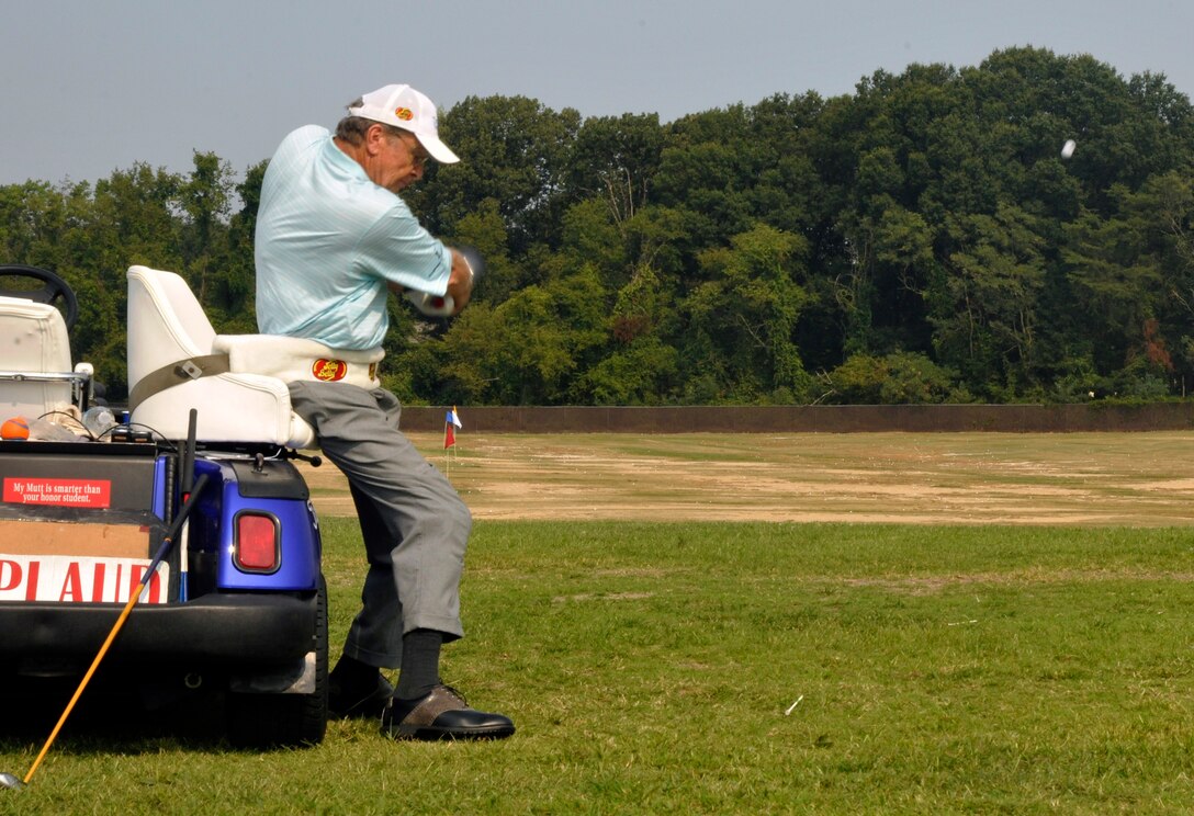 Dennis Walters, Andrews Leadership Series guest speaker, drives golf balls with the aid of a swivel seat secured to a golf cart at the Courses at Andrews Aug. 17, 2012. Walters, his dog Bucky, and their assistant Asher Grogg, tour the nation as The Dennis Walters Golf Show. Their show encourages viewers to continually persue their dreams despite life's challenges. (U.S. AIr Force photo/Senior Airman Lindsey Porter)