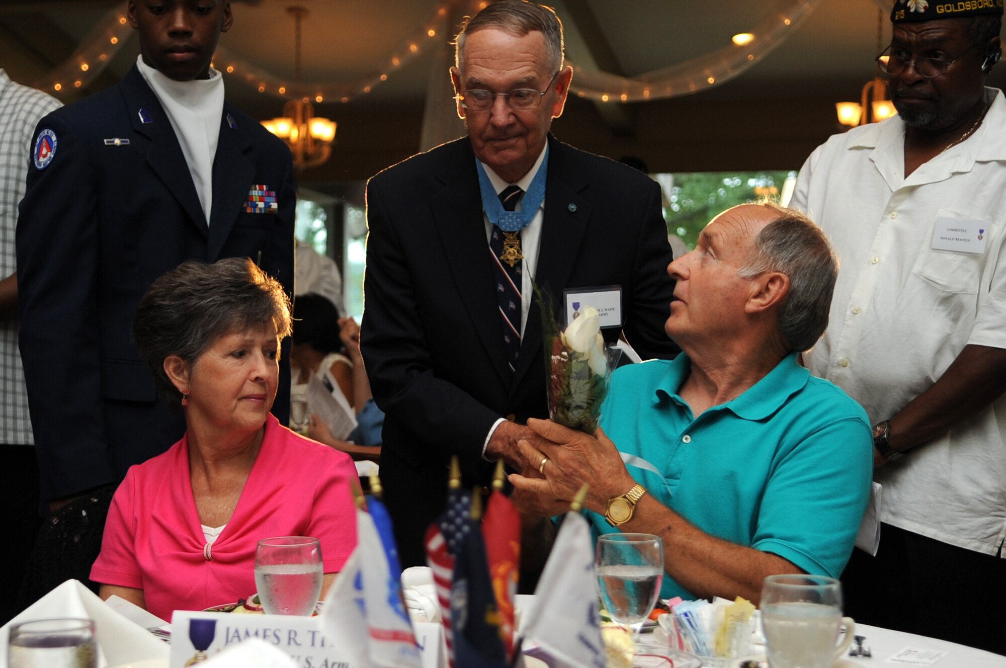 Retired U.S. Army Col. Walter Marm presents a flower to the parents of a Purple Heart recipient during the Purple Heart Banquet at the Walnut Creek Country Club in Goldsboro, N.C., Aug. 10, 2012. Families of Purple Heart recipients who were killed in action were invited to attend the banquet and recognized in honor of their loved ones. (U.S. Air Force photo/Airman 1st Class Aubrey Robinson/Released)