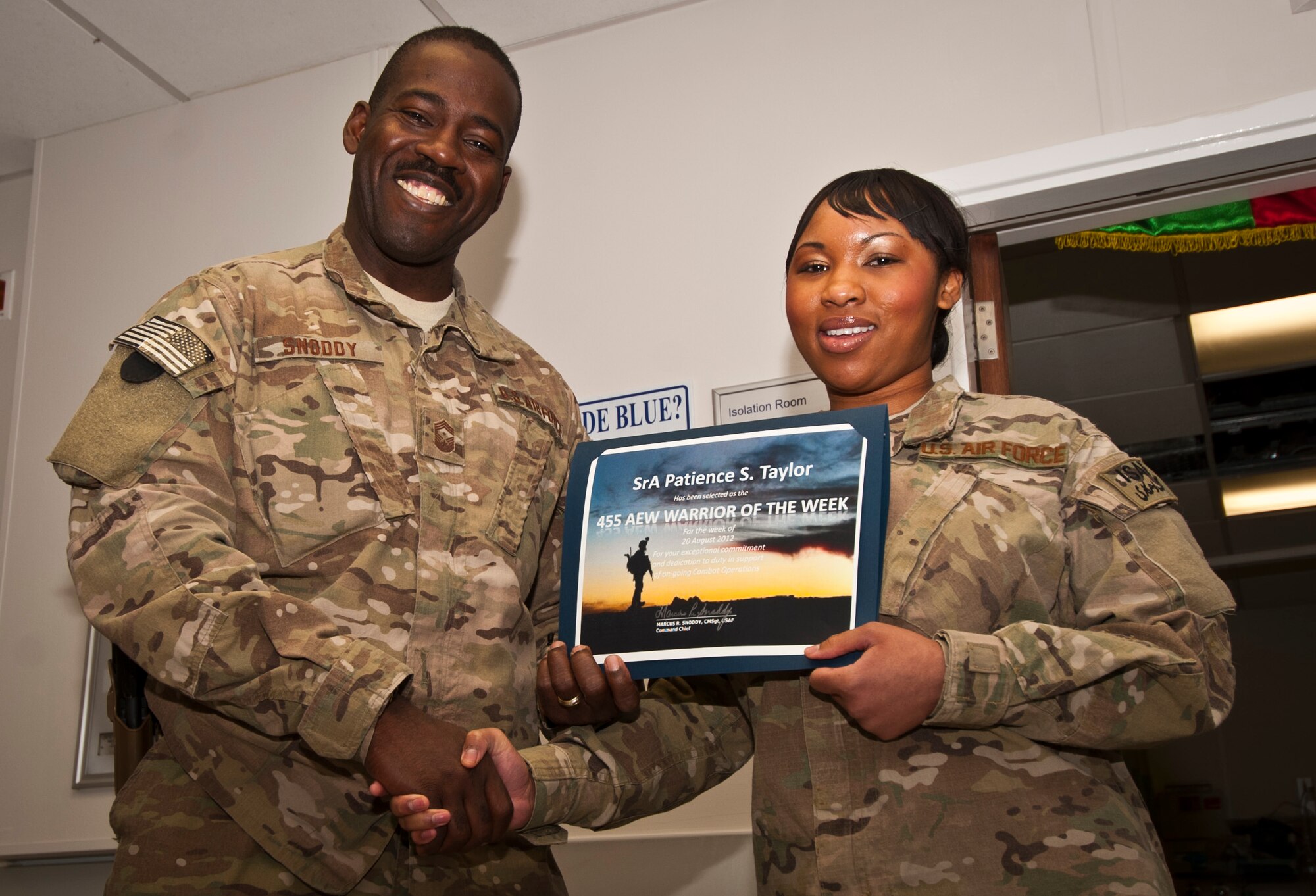 CMSgt Marcus Snoddy, 455th Air Expeditionary Wing command chief, presents the Warrior of the Week certificate to SrA Patience Taylor, 455th Expeditionary Medical Operations Squadron medical technician, at Bagram Airfield, Afghanistan, Aug. 20, 2012. As a Craig Joint Theater Hospital Intermediate Care Ward shift leader, Taylor coordinated duty assignments for four technicians ensuring care for 42 wounded and critically-ill patients, all while earning credits towards a degree from the Community College of the Air Force. (U.S. Air Force photo/Capt. Raymond Geoffroy)