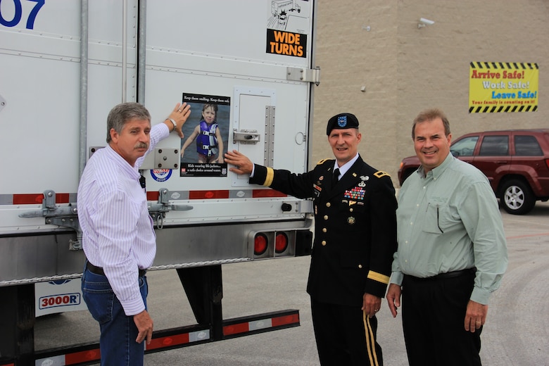 DALLAS, Texas — Brig. Gen. Thomas W. Kula, U.S. Army Corps of Engineers Southwestern Division commander (center), joins with Mr. Jim Franck, president of National Carriers, Inc. (right), and Johnny Branstine, maintenance director, to place a water safety sign on one of the 900 tractor trailer trucks owned by the company, Aug. 15, 2012.  