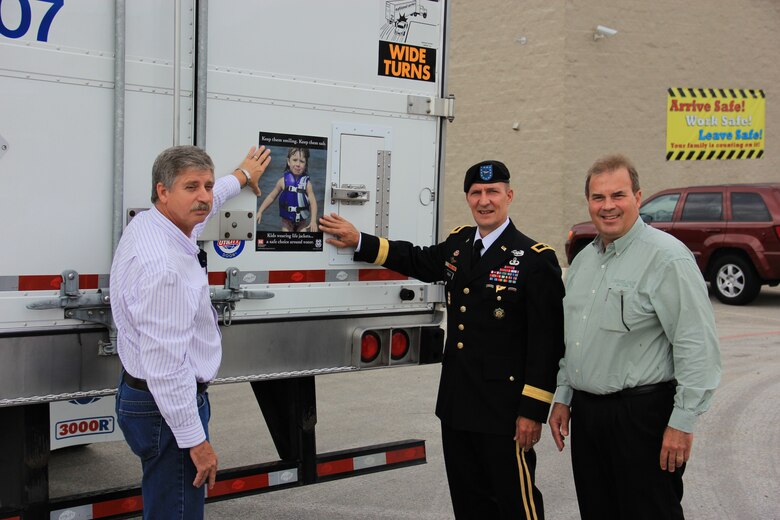 DALLAS, Texas — Brig. Gen. Thomas W. Kula, U.S. Army Corps of Engineers Southwestern Division commander (center), joins with Mr. Jim Franck, president of National Carriers, Inc. (right), and Johnny Branstine, maintenance director, to place a water safety sign on one of the 900 tractor trailer trucks owned by the company, Aug. 15, 2012.  