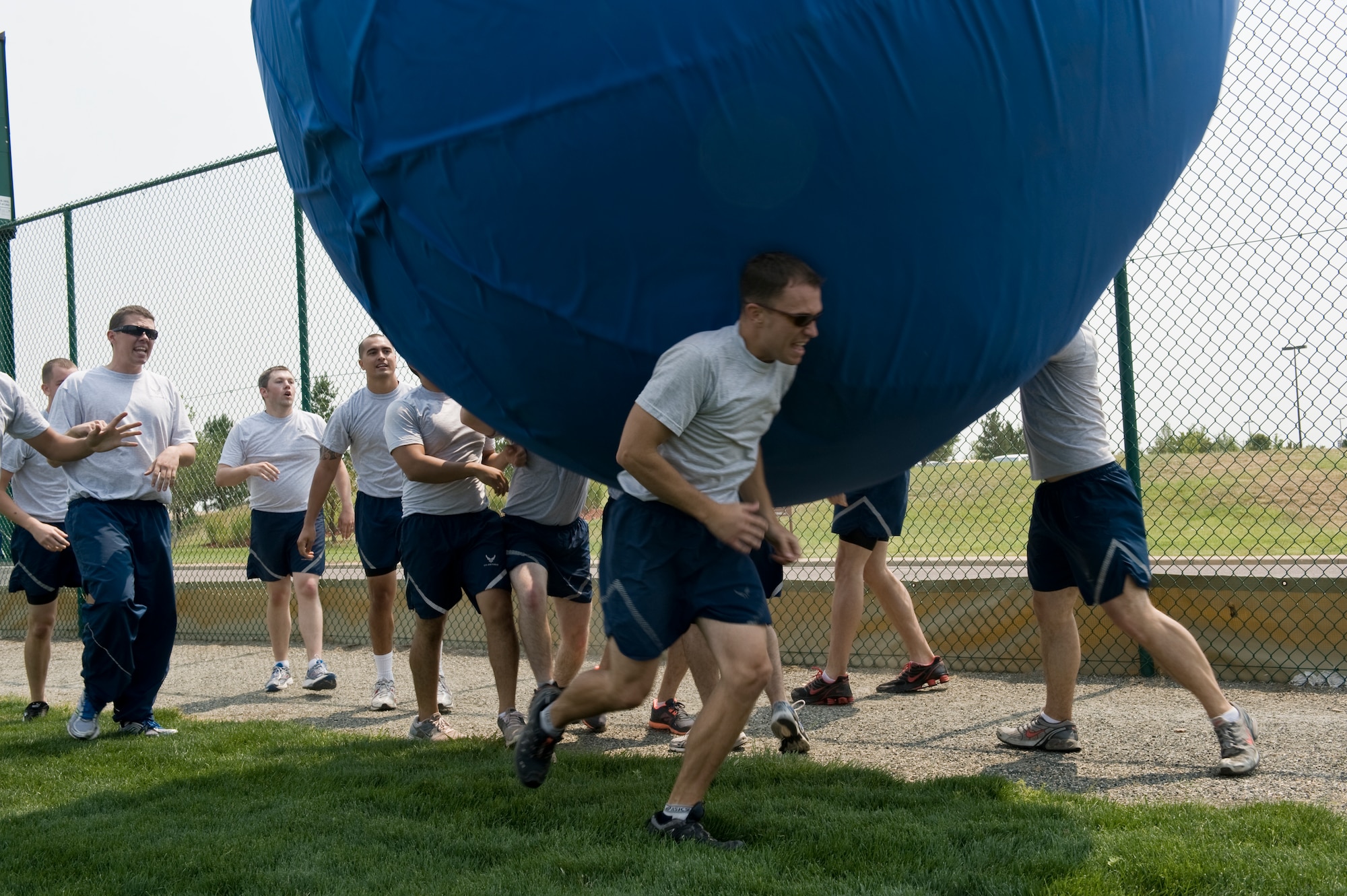 BUCKLEY AIR FORCE BASE, Colo. – A Team Buckley member runs to get clear of a giant blue ball his squadron members try to smother him with during Fun Fest Aug. 17, 2012.  The big ball event was one of many unique activities available to participants at the 460th Space Wing’s birthday celebration.  (U.S. Air Force photo by Airman 1st Class Phillip Houk)