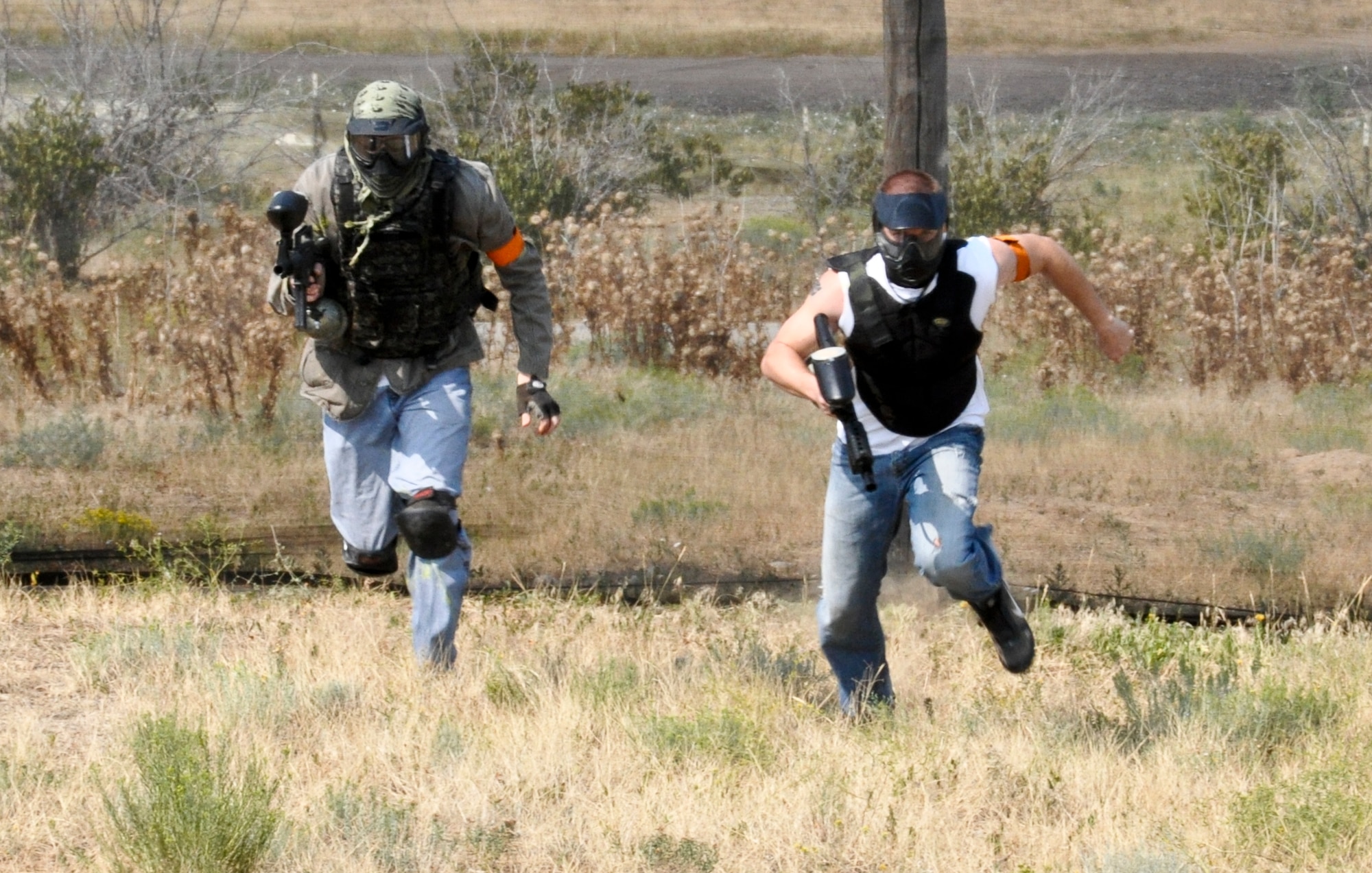 BUCKLEY AIR FORCE BASE, Colo. – Two Team Buckley members dash across the base paintball field during Fun Fest Aug. 17, 2012.  Paintball was one of the many events that took place during the 460th Space Wing birthday celebration.  (U.S. Air Force photo by Staff Sgt. Nicholas Rau)