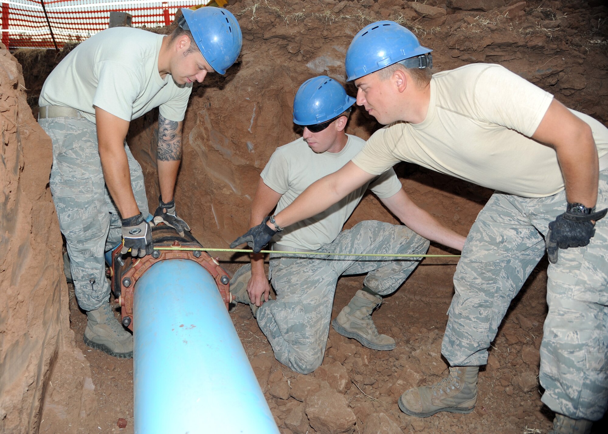 ALTUS AIR FORCE BASE, Okla. –Staff Sgt. Shawn Tesh, 97th Civil Engineer Squadron water and fuel systems maintenance journeyman, Senior Airman Corey Barr, 97th CES water and fuel systems maintenance journeyman, and Airman 1st Class Michael Wiggins, 97th CES water and fuel systems maintenance apprentice, measure a pipe behind a tanker fuel yard, Aug. 14, 2012. The 97th CES is working on a raw water irrigation project which satisfies a cost-conscious culture. The non-potable irrigation water will be used to water the Windy Trails Golf Course, saving the base around $48,000 on utility cost per year and saving the City of Altus around $12,000 on operational cost per year. (U.S. Air Force photo by Airman 1st Class Klynne Pearl Serrano / 97th Air Mobility Wing / Released)