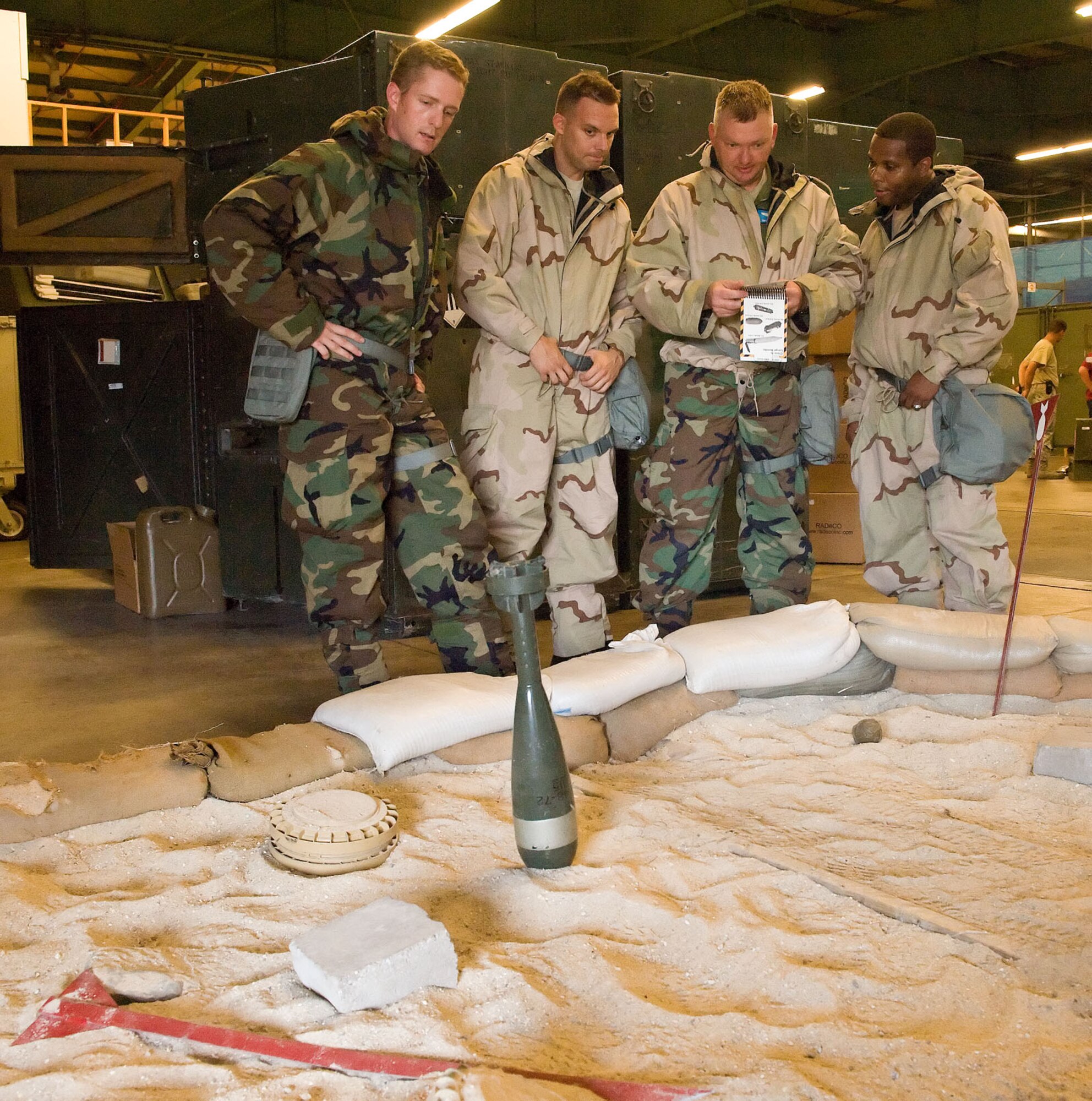 Service members use an Airman’s Manual to identify simulated unexploded ordnance during a Chemical Biological Radiological and Nuclear survival skills class Aug. 9, 2012, at Dover Air Force Base, Del. Identifying, marking and reporting are some of the responsibilities Airmen have to perform if assigned to a Post Attack Reconnaissance team. (U.S. Air Force photo by Roland Balik)