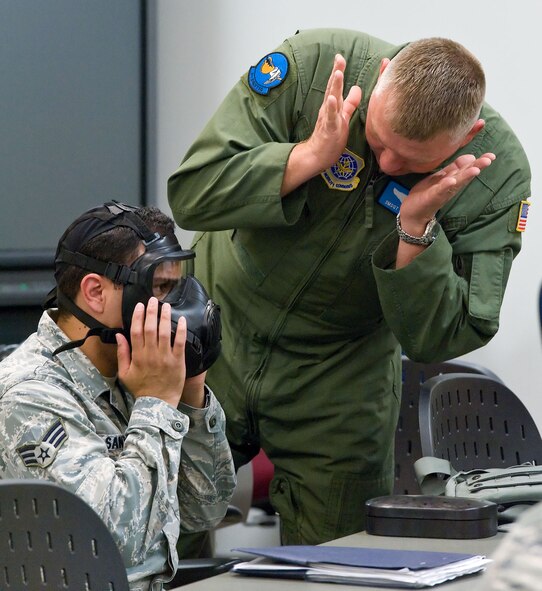 Senior Airman Abimael Santiago, left, and Senior Master Sgt. Mike Green, both flight engineers with the 9th Airlift Squadron, work together during the chemical mask session of a Chemical Biological Radiological and Nuclear survival skills training class Aug. 9, 2012, at Dover Air Force Base, Del. The 436th Civil Engineer Squadron Emergency Management and Training Section provides training to all active-duty personnel. (U.S. Air Force photo by Roland Balik)