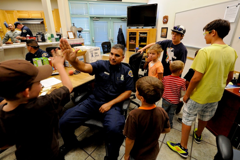 VANDENBERG AIR FORCE BASE, Calif. -- Charlie Martinez, a 30th Civil Engineer firefighter, dishes out high-fives during a tour of Fire Station 2 for the children at the 2012 Kids Fire Camp here Saturday, August 18, 2012. The fire camp was held to provide kids on base with fire safety information, hands-on learning and critical home fire safety skills. (U.S. Air Force photo/Staff Sgt. Levi Riendeau)