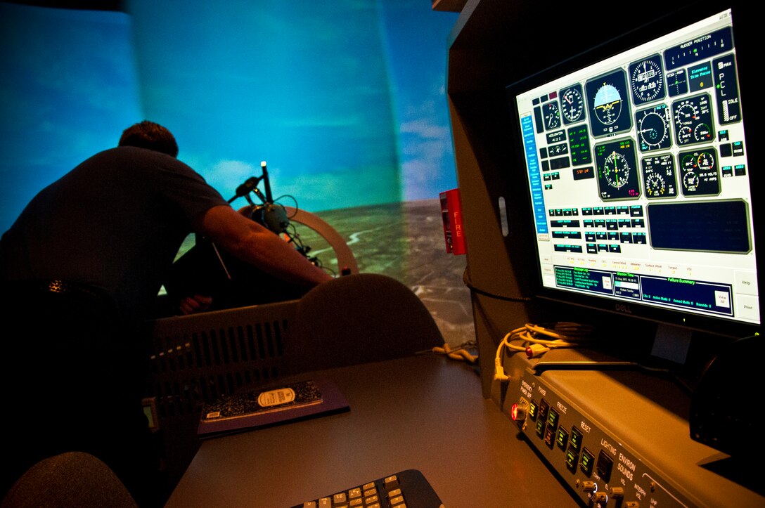 A simulator instructor steps away from his console to help a pilot at the controls of a T-6 simulator during a demo run at Jarvis Hall on Laughlin Air Force Base, Texas, Aug. 15, 2012. Laughlin’s T-6, T-38 and T-1 aircraft simulators help teach would-be pilots the foundation and basic skills necessary for Air Force pilots and help graduate Laughlin’s more than 300 pilot graduates each year. (U.S. Air Force photo/Senior Airman Scott Saldukas)