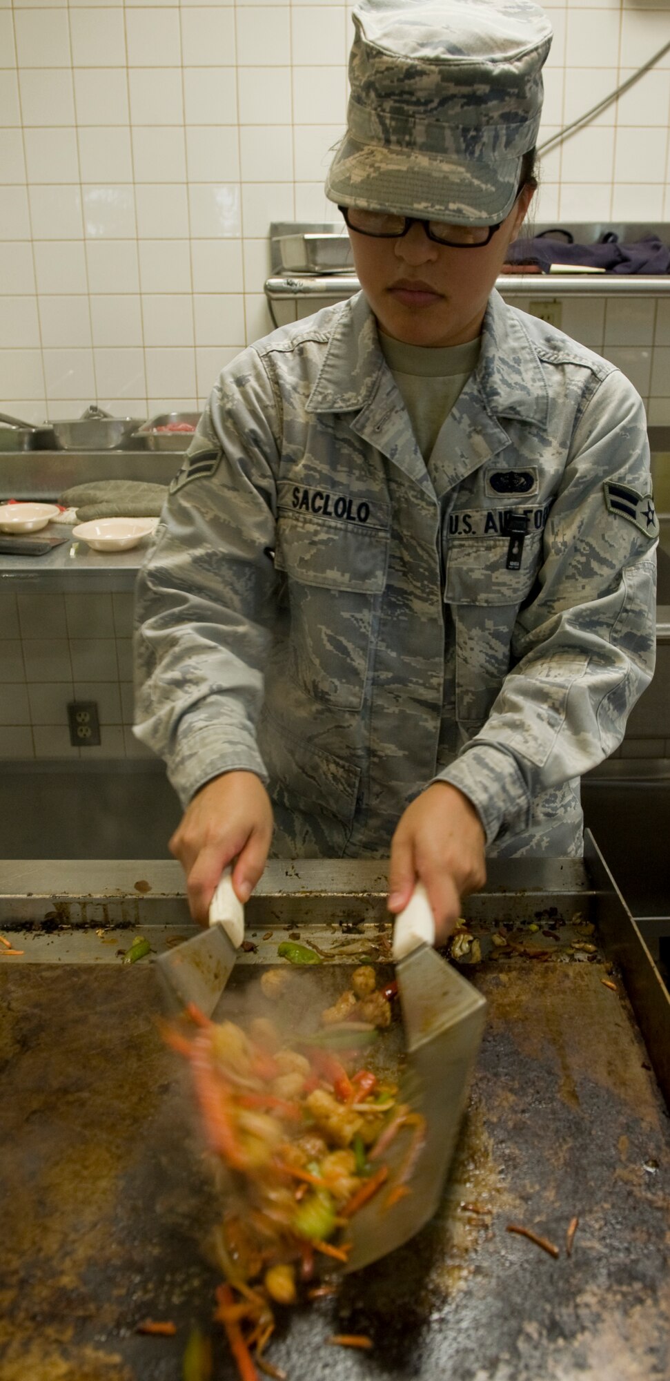 U.S. Air Force Airman 1st Class Yuki Saclolo, 7th Force Support Squadron, prepares an Asian style stir-fry as a special meal Aug. 16, 2012, at the Longhorn Dining Facility, Dyess Air Force Base, Texas. The dining facility features meals from several cultures each month to offer variety to its customers. Dyess begins the second phase of food operations as part of the Food Transformation Initiative beginning Oct. 1. The FTI program is designed to improve the quality, variety, and availability of food service operations. FTI will adjust installation food service operations to meet the lifestyles, needs and preferences of customers, and will restore a sense of community by expanding the eligibility of customers who can use the facilities. (U.S. Air Force photo by Airman 1st Class Peter Thompson/ Released)