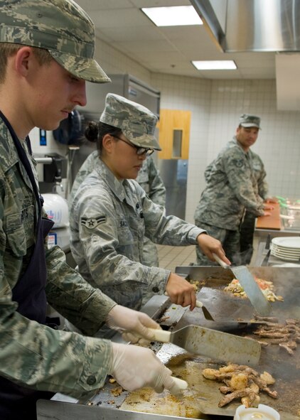 Airman 1st Class Steven Roberts, left, and A1C Yuki Saclolo, 7th Force Support Squadron, prepare Asian style stir-fry as a special meal Aug. 16, 2012, at the Longhorn Dining Facility, Dyess Air Force Base, Texas. The dining facility features meals from several cultures each month to offer variety to its customers. Dyess begins the second phase of food operations as part of the Food Transformation Initiative beginning Oct. 1. The FTI program is designed to improve the quality, variety, and availability of food service operations. FTI will adjust installation food service operations to meet the lifestyles, needs and preferences of customers, and will restore a sense of community by expanding the eligibility of customers who can use the facilities. (U.S. Air Force photo by Airman 1st Class Peter Thompson/ Released)
