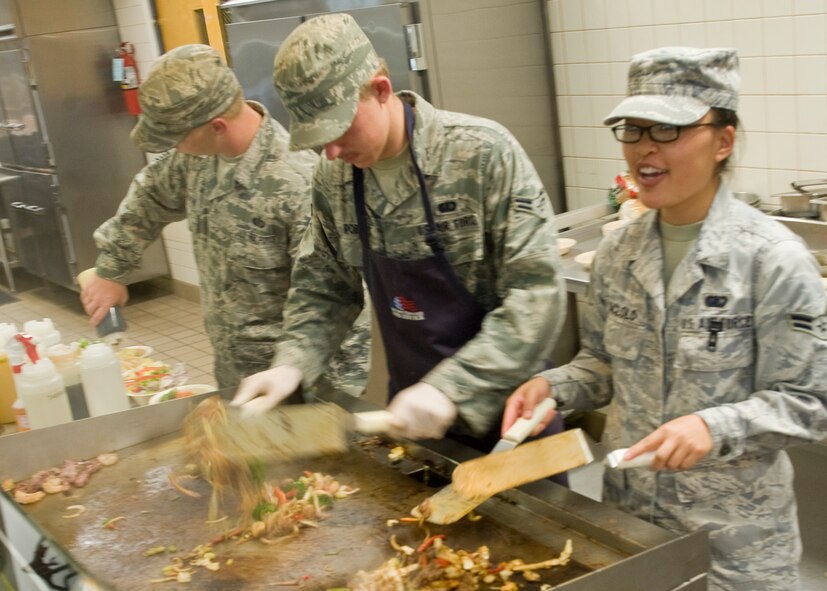Staff Sgt. Dustin McBroom, left, Airman 1st Class Steven Roberts, center, and A1C Yuki Saclolo, right, 7th Force Support Squadron, prepare Asian style stir-fry as a special meal Aug. 16, 2012, at the Longhorn Dining Facility, Dyess Air Force Base, Texas. The dining facility features meals from several cultures each month to offer variety to its customers. Dyess begins the second phase of food operations as part of the Food Transformation Initiative beginning Oct. 1. The FTI program is designed to improve the quality, variety, and availability of food service operations. FTI will adjust installation food service operations to meet the lifestyles, needs and preferences of customers, and will restore a sense of community by expanding the eligibility of customers who can use the facilities. (U.S. Air Force photo by Airman 1st Class Peter Thompson/ Released)