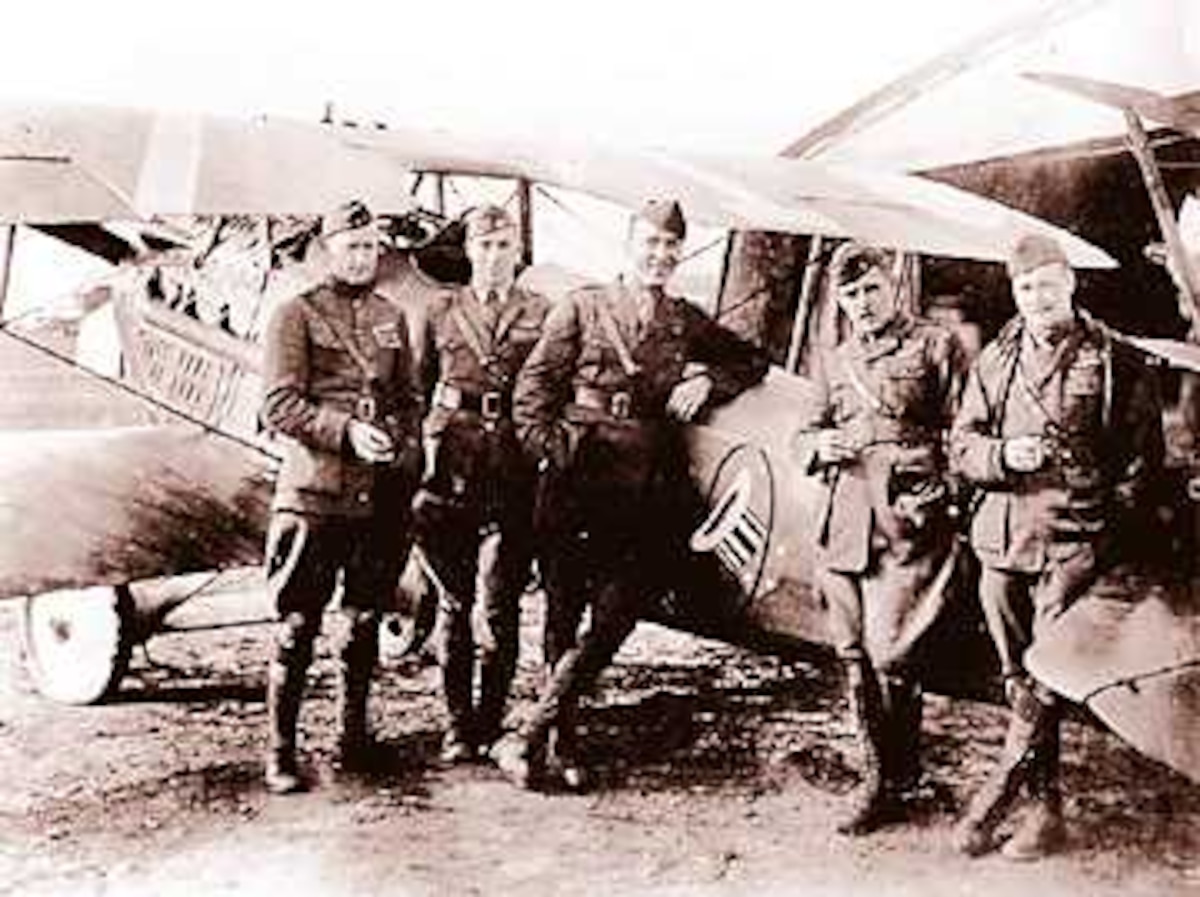 Capt. Eddie Rickenbacker, America's Ace of Aces in World War I, poses with other members of the 94th Pursuit Squadron, the famous "Hat in the Ring" squadron, while assigned to Selfridge Field following the close of World War I. Rickenbacker and the 94th were part of the 1st Pursuit Squadron that was assigned to Selfridge in the 1920s. Rickenbacker is the third from the left, next to the Hat in the Ring insignia on the aircraft.