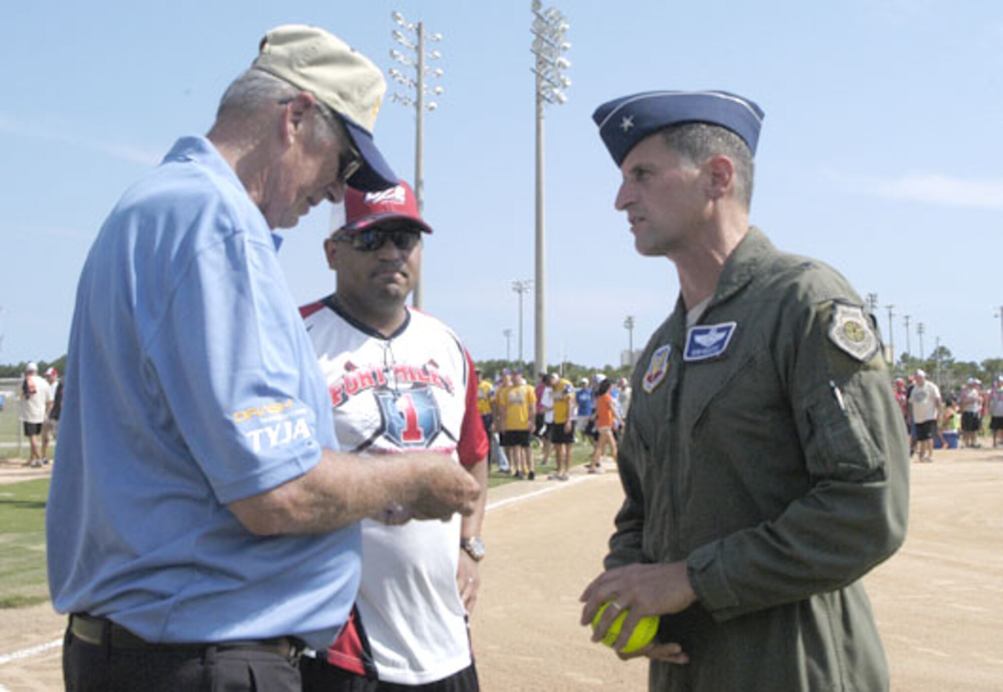 Master Sgt. Robert Robinson, Det. 1, 101 Air and Space Operations Group logistics superintendent,  watches as  Roger Hockey, United States Specialty Sports Association (USSA) Military/Corporate/ Law Enforcement Program Director, looks at the coin presented to him by Brig. Gen. Robert Beletic, 1st Air Force (Air Forces Northern) Vice Commander following opening ceremonies of the 2012 USSSA Military World Softball Tournament August 16 at Frank Brown Park in Panama City Beach. More than 100 military teams participated in the four-day tournament, including the Wounded Warriors Amputee team. 