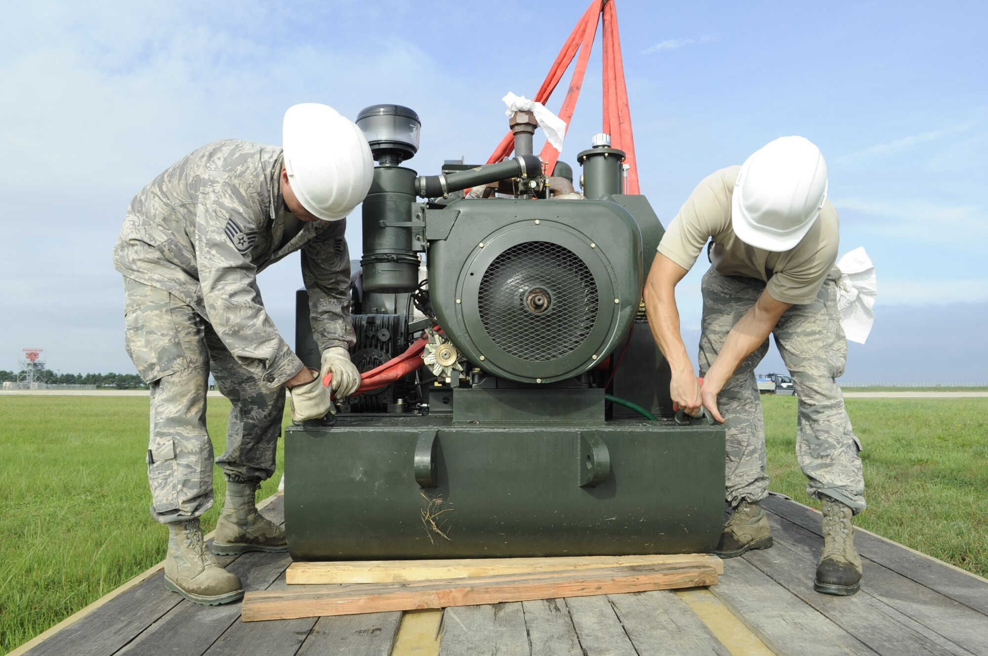 Staff Sgt. Sheldon Mellott, left, 8th Civil Engineer Squadron heavy equipment operator, and Staff Sgt. Michael Brennan, 8th CES power production craftsman, unhook an aircraft arresting system after loading it onto a flatbed at Kunsan Air Base, Republic of Korea, Aug. 18, 2012. After nearly a foot of rainfall here last week, the braking systems were under water and had to be moved. (U.S. Air Force photo/Senior Airman Brigitte N. Brantley)