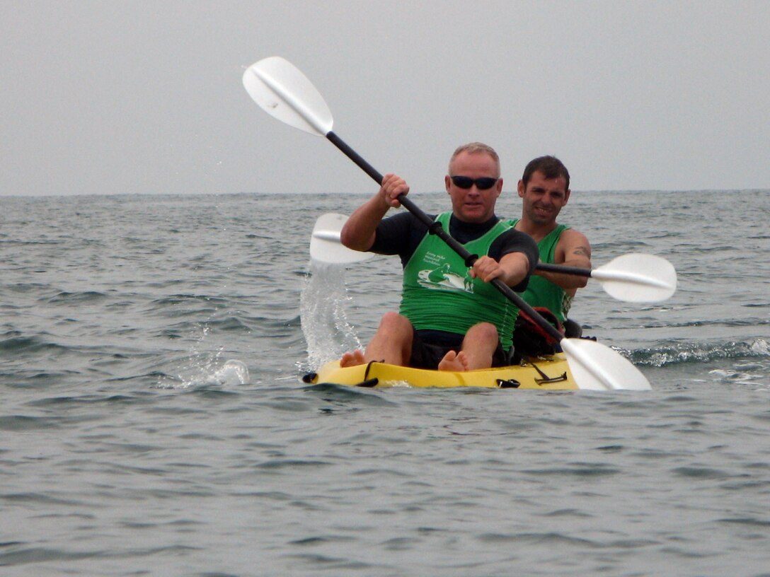 Two Marines from the Wounded Warrior Battalion-West paddle board team paddles a kyak behind a teamate during the paddle board practice at the Marine Corps Base Camp Pendleton Marina, Aug 21. WWBn-West will be the only relay team to compete in the Catalina Classic paddle board race, Aug. 26.