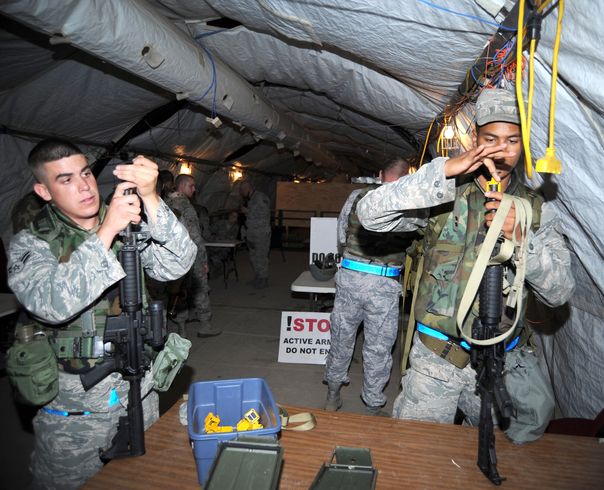 Two Airmen with the 355th Civil Engineer Squadron affix safety devices on the front of their rifles during a night training exercise at Davis-Monthan Air Force Base, Ariz., August 16. The Airmen were trained on self-aid buddy care, night vision goggles training, 9-line medevac training, and post attack reconnaissance with mission oriented protective posture gear. (U.S. Air Force photo by Airman 1st Class Michael Washburn/Released)