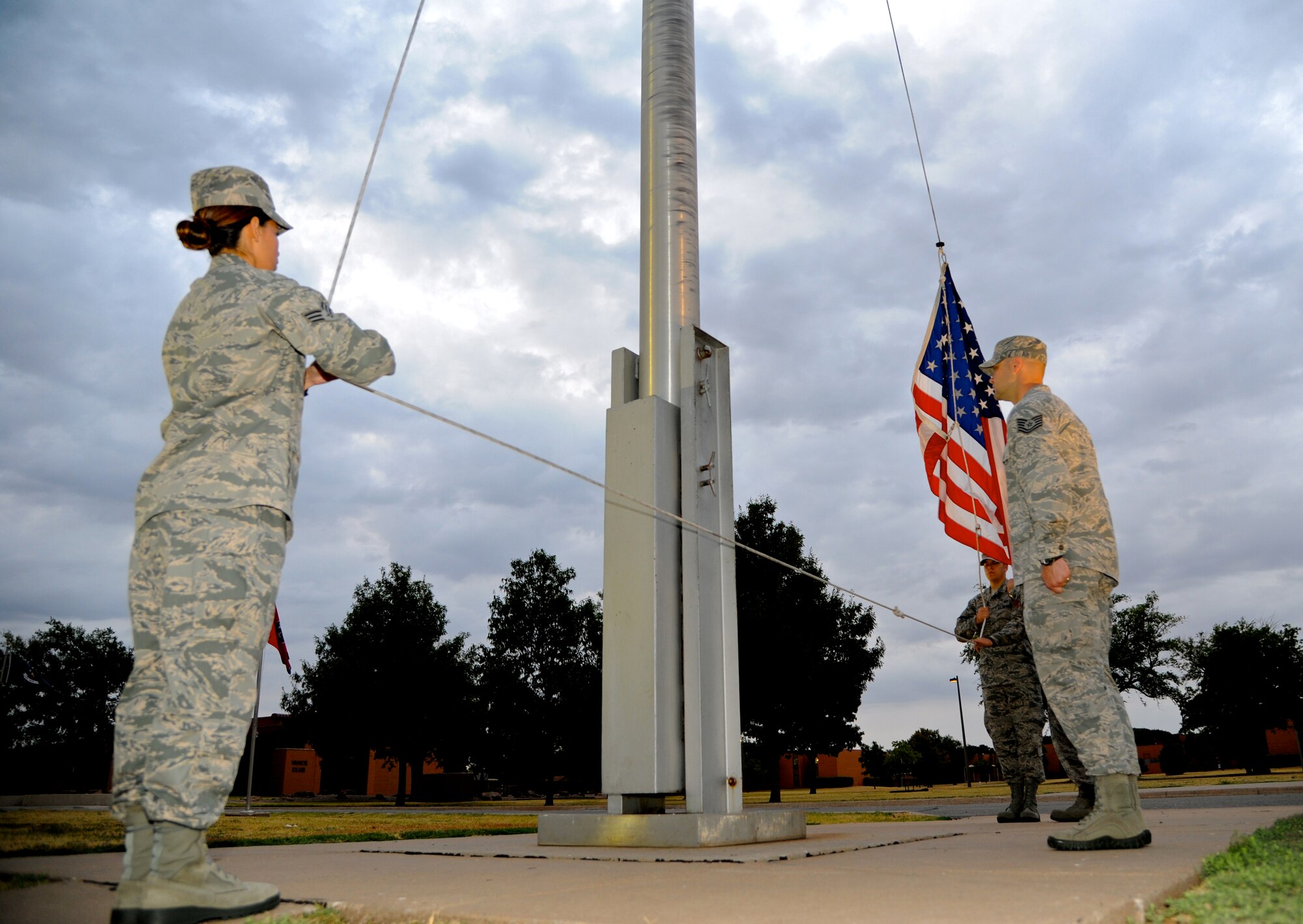 Senior Airman Rosa Garrette, left, 71st Force Support Squadron; Tech. Sgt. Jeremy Sykora, 71st Communications Squadron; and Senior Airman James Ward, background, 71st Operations Support Squadron, raise the United States flag during reveille to kick off the Staff Sergeant Summit held Aug. 18 at Vance Air Force Base, Okla. (U.S. Air Force photo/ Airman 1st Class Frank Casciotta)