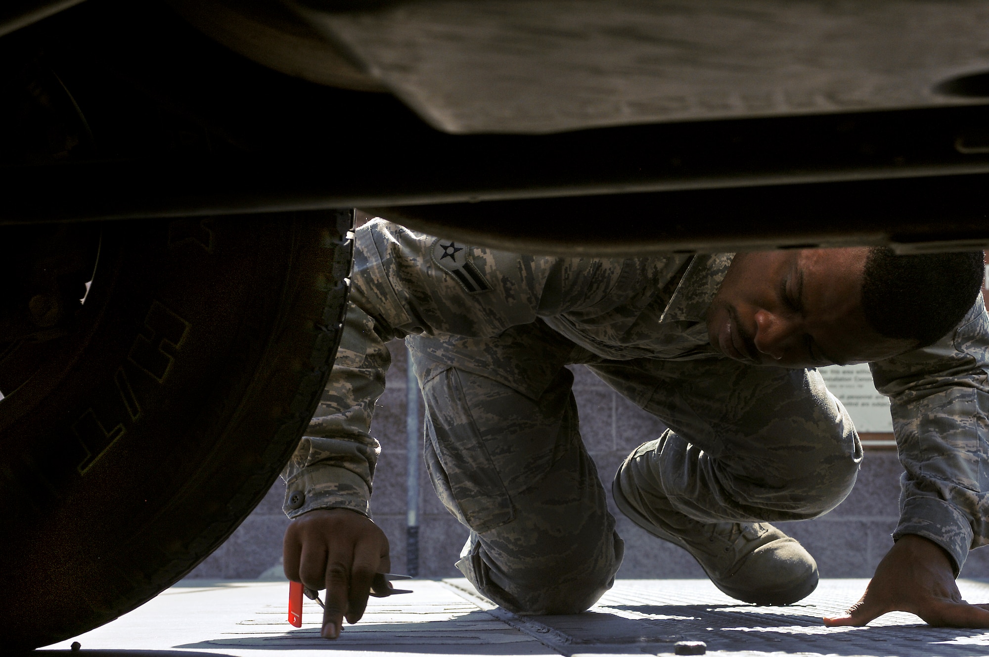 Airman 1st Class Floyd Jones Jr., 57th Operational Support Squadron airfield management specialist, removes a foreign object from under a truck tire during a Foreign Object Debris check Aug. 21, 2012, at Nellis Air Force Base, Nev. FOD is potentially dangerous on airfields because it can be sucked into aircraft engines causing damage and endangering lives. (U.S. Air Force photo by Senior Airman Jack Sanders)
