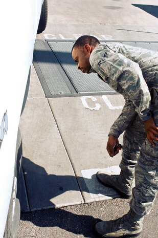 Airman 1st Class Floyd Jones Jr., 57th Operational Support Squadron airfield management specialist, checks a tire for Foreign Object Debris during a FOD check Aug. 21, 2012, at Nellis Air Force Base, Nev. Jones aids in managing the flightline drivers license program. (U.S. Air Force photo by Senior Airman Jack Sanders)