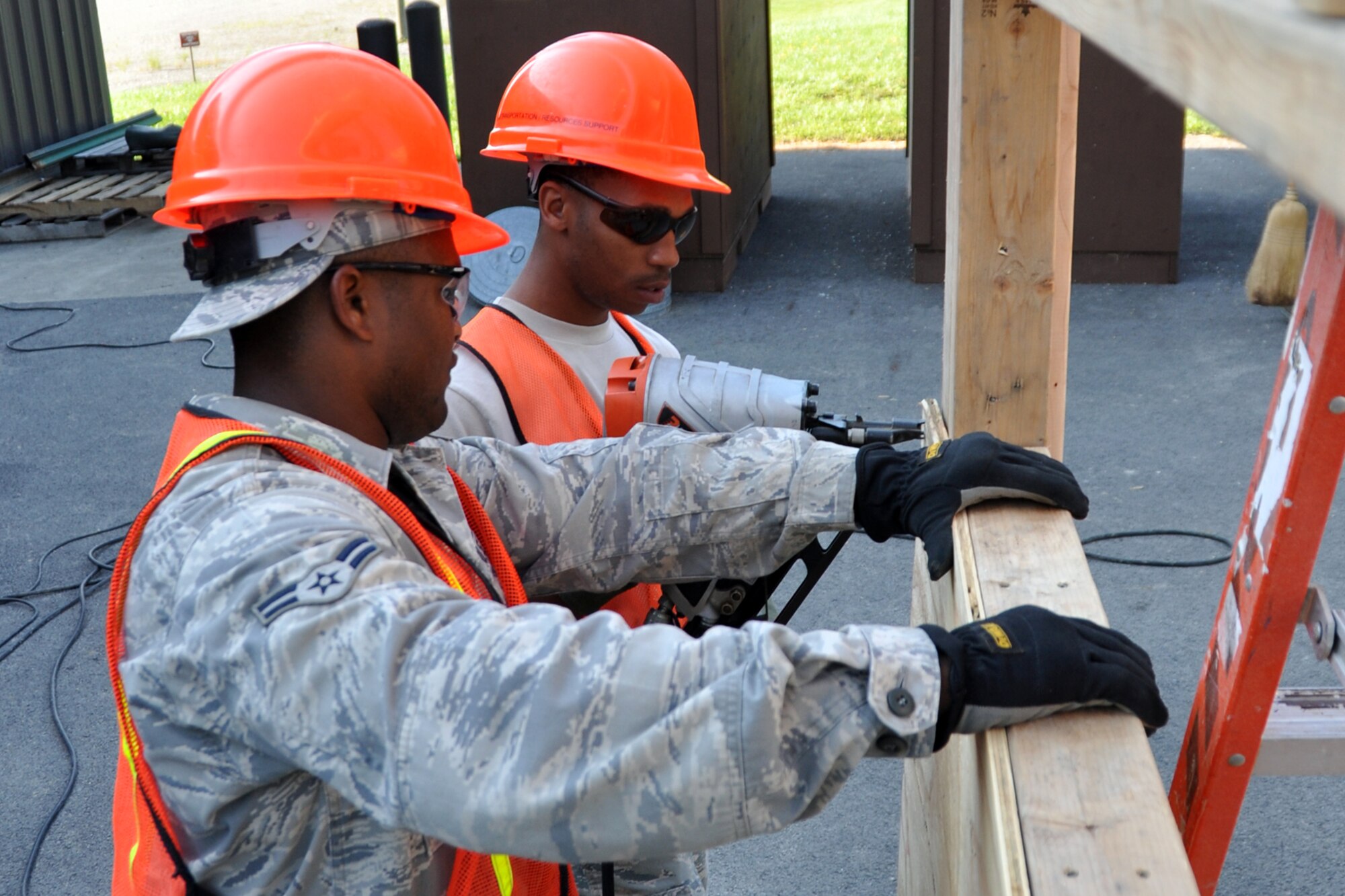 Airman 1st Class Brandon Curry, electrician, holds a piece of plywood in place as Senior Airman Trashawn Hudson, a heating, ventilation, air conditioning and refrigeration technician nails it to a frame at Youngstown Air Reserve Station, Vienna, Ohio, Aug. 16, 2012. Both Airmen are assigned to the 307th Civil Engineer Squadron from Barksdale Air Force Base, La., and were part of a detail that spent two weeks at Youngstown assisting the 910 Civil Engineer Squadron build a Prime Base Engineer Emergency Force (Prime BEEF) training area. (U.S. Air Force photo by Master Sgt. Jeff Walston)