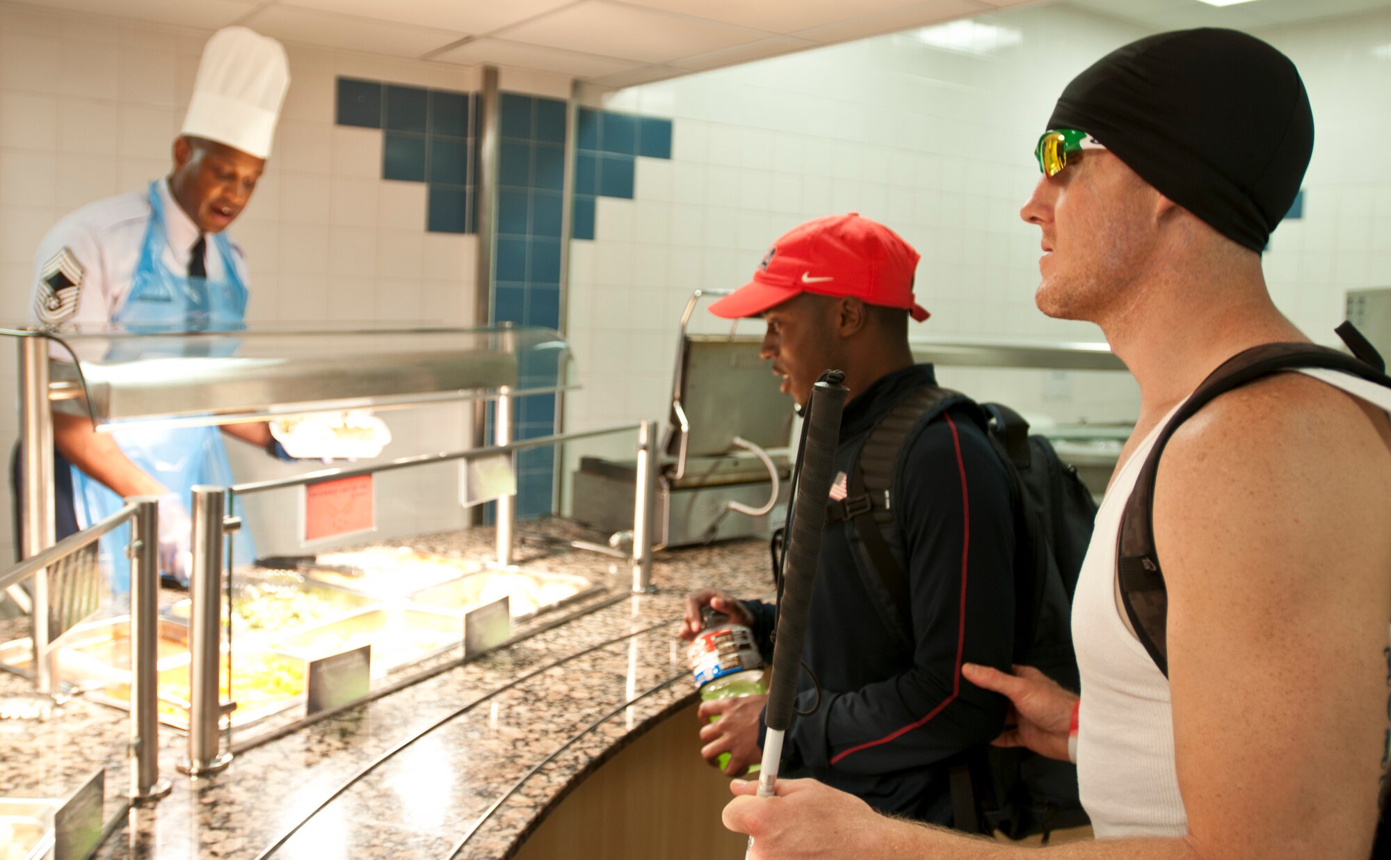 ROYAL AIR FORCE LAKENHEATH, England – Tanner Gers (right), U.S. Paralympian, and Sean Ewing (middle), his guide, are served lunch by Chief Master Sgt. Michael McMillan, 48th Mission Support Group superintendant, at the Knight’s Table Aug. 20, 2012. Gers is competing in the long jump and the 100-meter relay. More than 50 U.S. Paralympians and hopefuls will be honing their skills and making final preparations here Aug. 18 through 25 for competition in the London 2012 Paralympic Games. (U.S. Air Force photo by Staff Sgt. Stephen Linch)