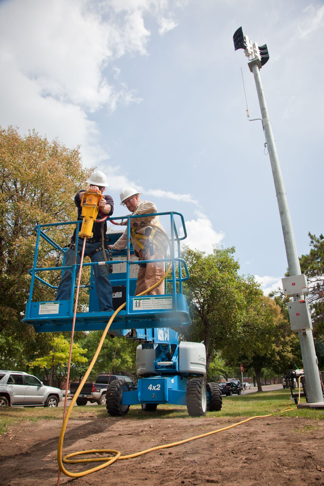 Civil engineer workers Dusty Hawkins and Phil Winkels work to install the grounding bars for the new "giant voice" communications system on base before a rainstorm.  (U.S. Air Force Photo/Shannon McKay)