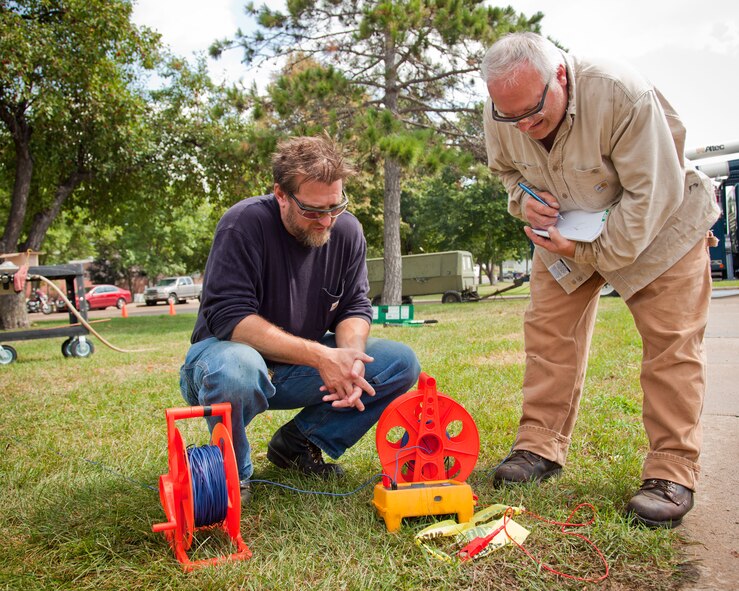 Civil engineer workers Dusty Hawkins and Phil Winkels check the conductivity of the grounding bars for the new "giant voice" communications system being installed on base.  (U.S. Air Force Photo/Shannon McKay)