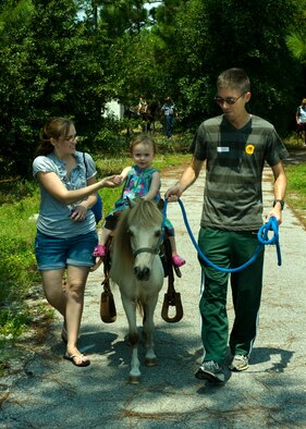 Renee Havron, left, wife of Staff Sgt. Joshua Havron, 1st Special Operations Communications Squadron, holds on to her daughter, Lily, 2, as she rides a pony, Bucky, led by Staff Sgt. Michael Larson, a weather forecaster from 1st Special Operations Support Squadron and event volunteer, during the Commando Agencies Reaching Everyone carnival at the Community Park at Hurlburt Field, Fla., Aug. 18, 2012. Lily was one of hundreds of children who had the opportunity to ride a horse at the event. (U.S. Air Force photo by Airman 1st Class Nigel Sandridge)