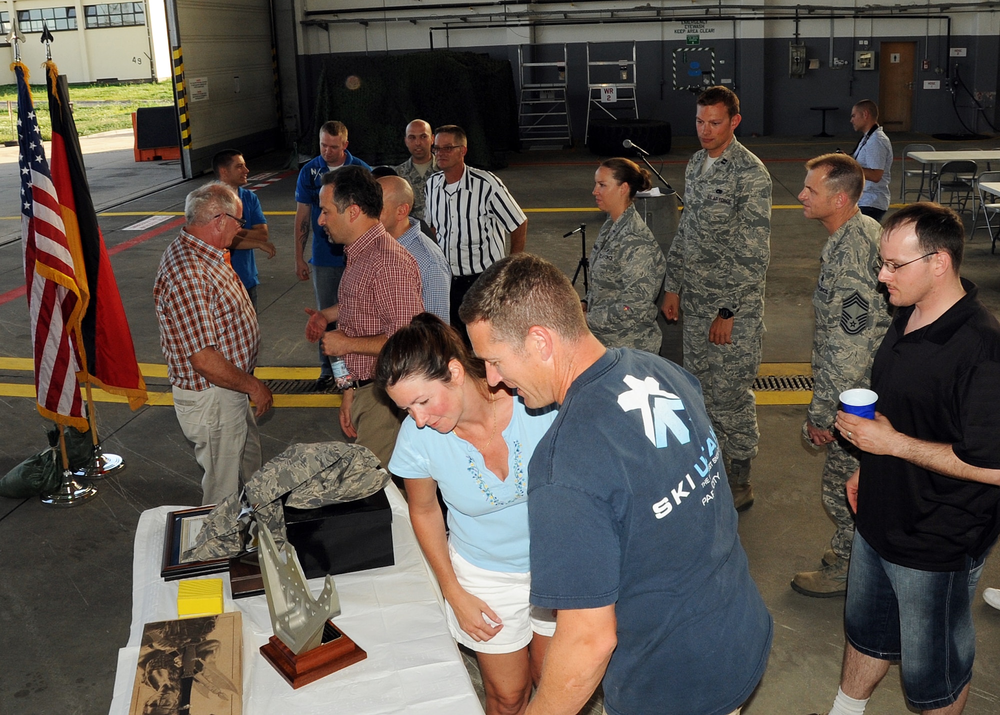 SPANGDAHLEM AIR BASE, Germany – Airmen, family and friends line up to shake hands with and look at the parting gifts of Alois Schmitz, 52nd Component Maintenance Squadron fuels systems repair shop, during his retirement ceremony Aug. 17 in Hangar 3 here. Schmitz is retiring after nearly four decades of service to the U.S. Air Force. (U.S. Air Force photo by Staff Sgt. Daryl Knee/Released)