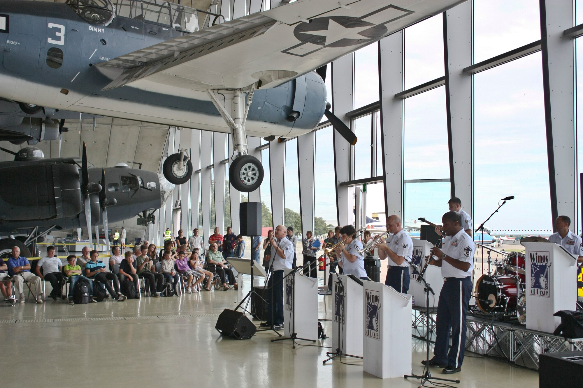 CAMBRIDGESHIRE, England - The U.S. Air Forces in Europe Wings of Dixie band perform in front of crowd inside the American Air Museum during the Imperial War Museum's American Air Day at Duxford, U.K., Aug. 17, 2012. The day provided the local community the opportunity to see what Airmen stationed in England do on a daily basis. Events included a mix of flying and ground-based activities that featured personnel from the 48th Fighter Wing, the 100th Air Refueling Wing and the 501st Combat Support Wing. (U.S. Air Force photo by Senior Airman Connor Estes)