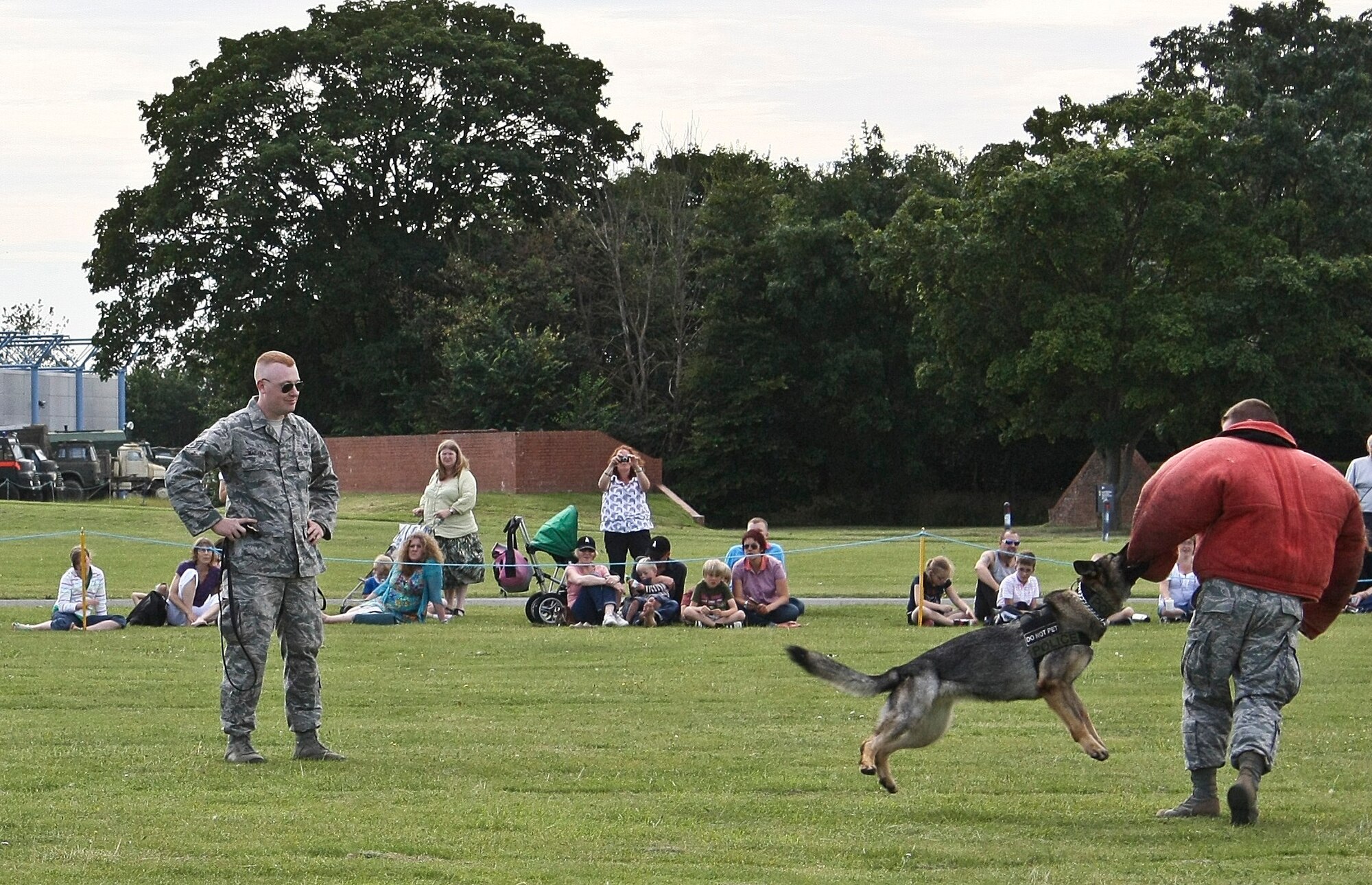 CAMBRIDGESHIRE, England - Gina, 48th Security Forces Squadron military working dog, bites Airman 1st Class Eric Harr (right), 48th SFS patrolman, as Staff Sgt. Chris Maziarka (left), 48th SFS military working dog handler, orders her to do so, during a demonstration at the Imperial War Museum's American Air Day in Duxford, U.K., Aug. 17, 2012. The day provided the local community the opportunity to see what Airmen stationed in England do on a daily basis. Events included a mix of flying and ground-based activities that featured personnel from the 48th Fighter Wing, the 100th Air Refueling Wing and the 501st Combat Support Wing. (U.S. Air Force photo by Senior Airman Connor Estes)