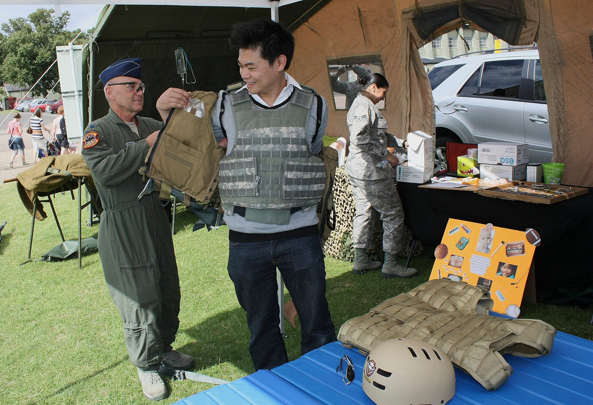 CAMBRIDGESHIRE, England - Lt. Col. Mike Ripley, 488th Intelligence Squadron flight surgeon, helps Doctor Yuen Man from Kingston, England, put on a Kevlar jacket at the 48th Medical Group display tent during the Imperial War Museum's American Air Day at Duxford, U.K., Aug. 17, 2012. The day provided the local community the opportunity to see what Airmen stationed in England do on a daily basis. Events included a mix of flying and ground-based activities that featured personnel from the 48th Fighter Wing, the 100th Air Refueling Wing and the 501st Combat Support Wing. (U.S. Air Force photo by Senior Airman Connor Estes)