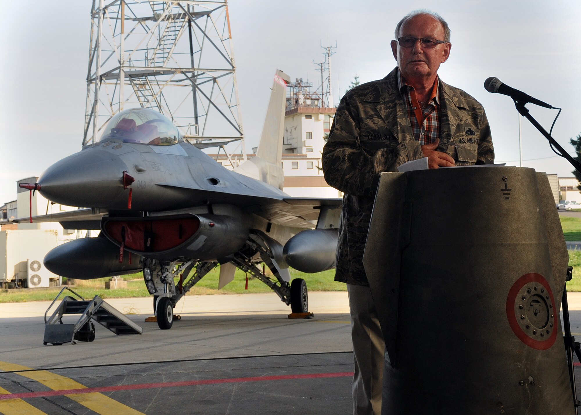 SPANGDAHLEM AIR BASE, Germany -- Alois Schmitz, 52nd Component Maintenance Squadron fuels systems repair shop, speaks to the attendees of his retirement ceremony Aug. 17 in Hangar 3 here. Schmitz donned a custom Airman Battle Uniform blouse before thanking the more than 100 Airmen, family and friends who had attended the ceremony. The name tag on the uniform reads “Cobra Schmitz,” which was Schmitz’ unofficial radio call sign. (U.S. Air Force photo by Staff Sgt. Daryl Knee/Released)