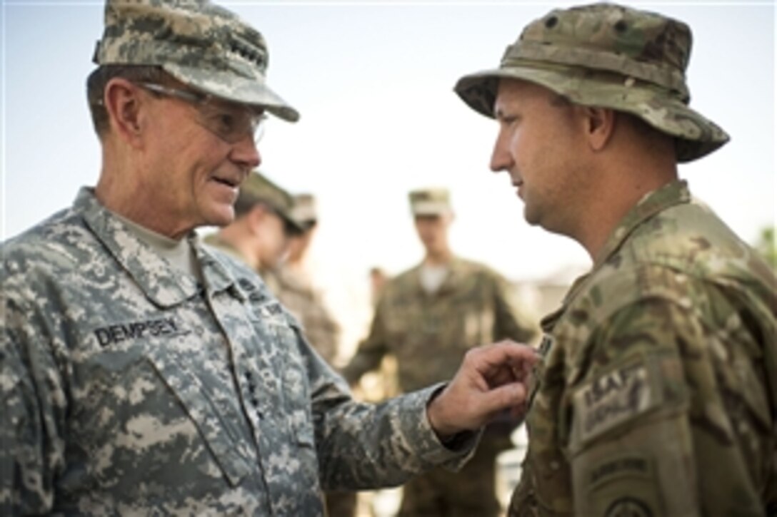 U.S. Army Gen. Martin E. Dempsey, chairman of the Joint Chiefs of Staff, presents a medal to a soldier stationed on Bagram Airfield in Afghanistan, Aug. 21, 2012. 