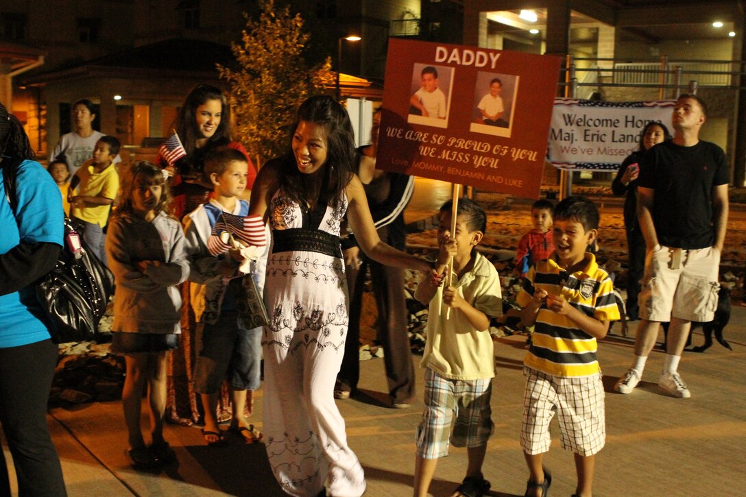 Judy Heaps, a native of Orem, Utah, runs toward buses along with her two sons Benjamin, 6, and Luke, 5, at the sight of her husband, Master Gunnery Sgt. Cody Heaps, an intelligence chief with 1st Marine Division (Forward), during a homecoming event here, Aug. 22. The Division was deployed to Afghanistan in support of Operation Enduring Freedom and headed Task Force Leatherneck, the ground combat element of Regional Command Southwest.