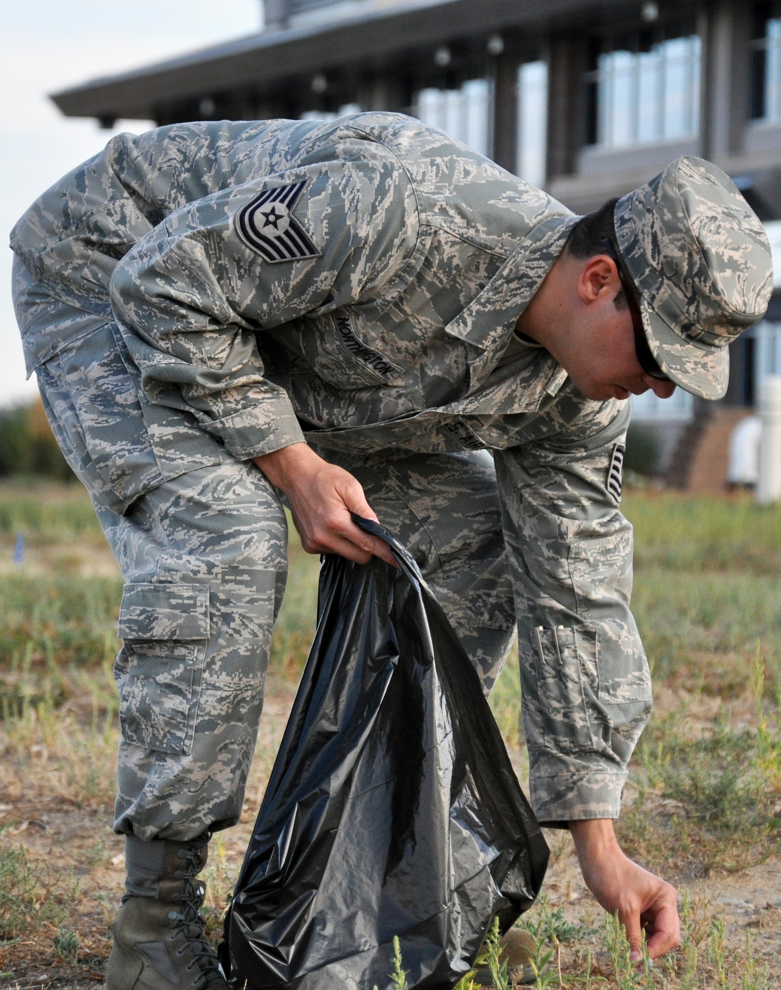 BUCKLEY AIR FORCE BASE, Colo. – Tech Sgt. Kenneth Northington, 460th Space Wing Safety Office, picks up trash behind the command building during a base beautification event Aug. 23, 2012.  “Ridding the base of debris, trash (and other hazards) helps prevent possible injury from trips, slips and falls,” he said.  “Also it gives us the opportunity to identify any possible hazardous materials or any safety issues that might not otherwise be identified.”  (U.S. Air Force photo by Staff Sgt. Nicholas Rau)  