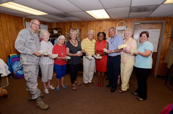 Col. Tim Tarchick, 94th Airlift Wing commander, joins volunteers from the Dobbins Thrift Store, 94th Airlift Wing Safety, and the 94th Logistics Readiness Squadron to present Angela Pedersen, Airmen Family Readiness Office director, with cash and a check totaling $1,613 on Aug. 23. The funds raised from proceeds from the Corn and Sausage Roast held earlier this year and from sales at the thrift store, will be used to provide Airmen with emergency financial assistance. (U.S. Air Force photo/Don Peek)